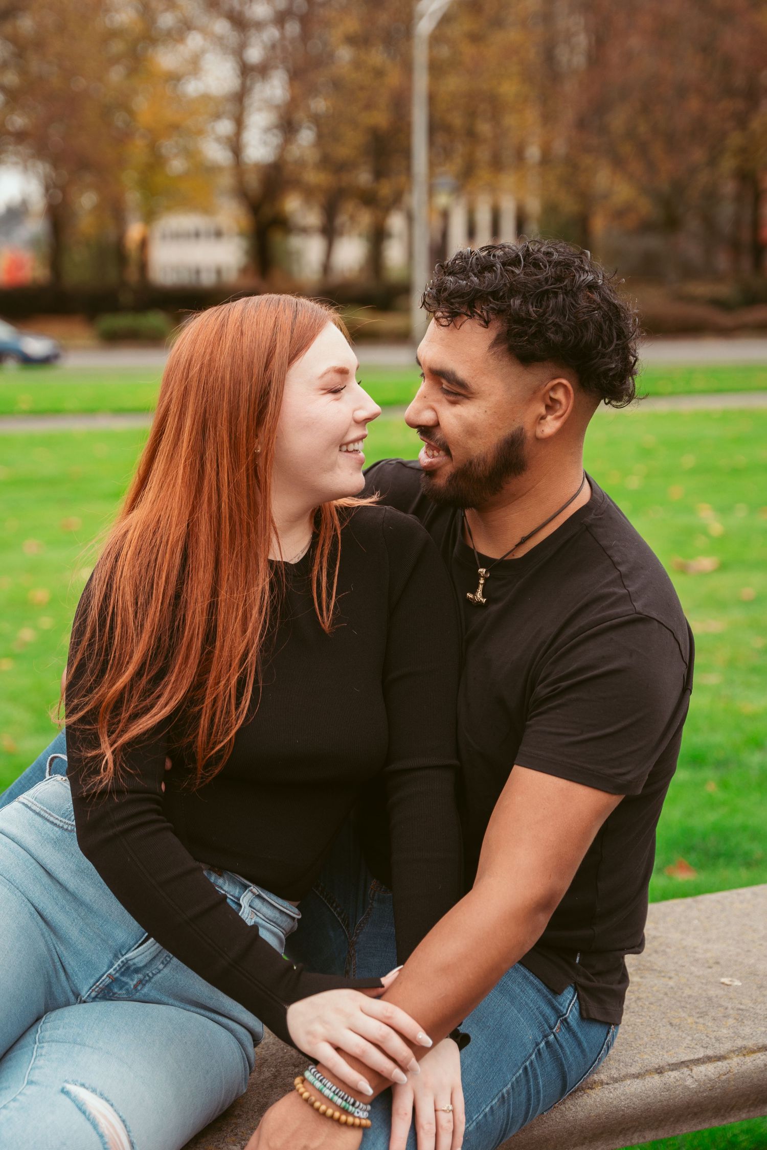 A couple shares an intimate moment together on a bench during autumn.