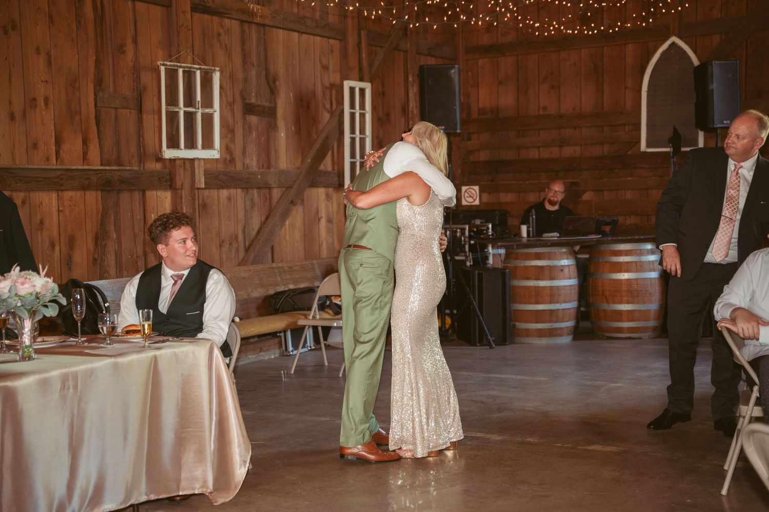 Wedding party dancing in a rustic barn venue decorated with twinkle lights and paper lanterns.