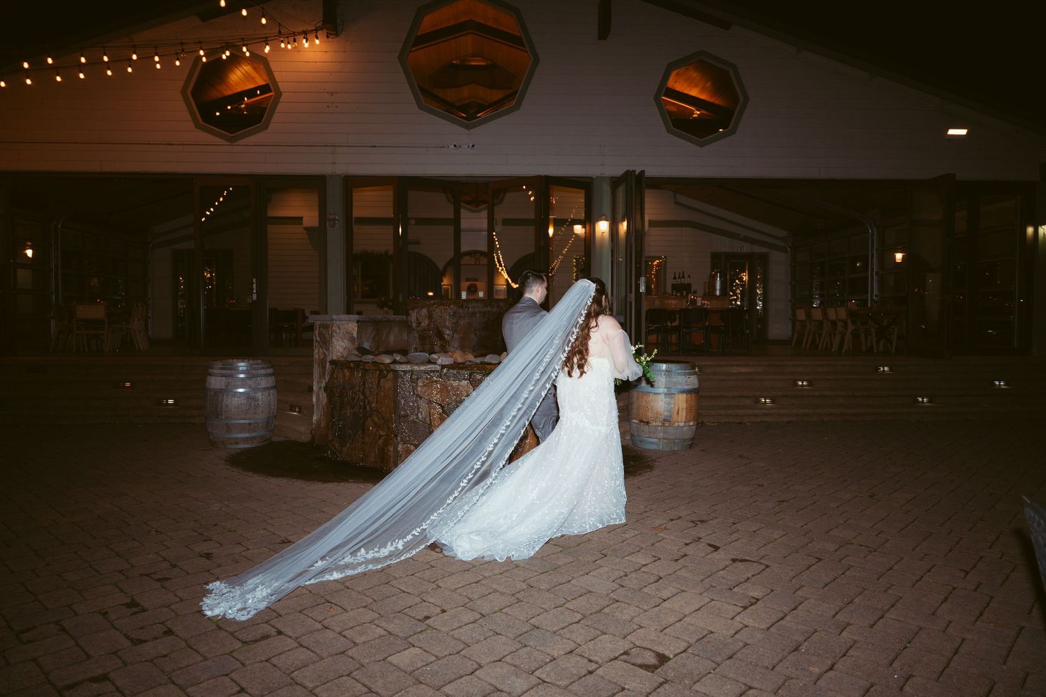 Wedding reception area decorated with string lights and elegant white drapery.