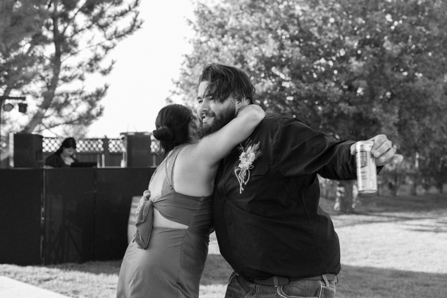 A black and white photo of a couple dancing together outdoors in a candid moment.