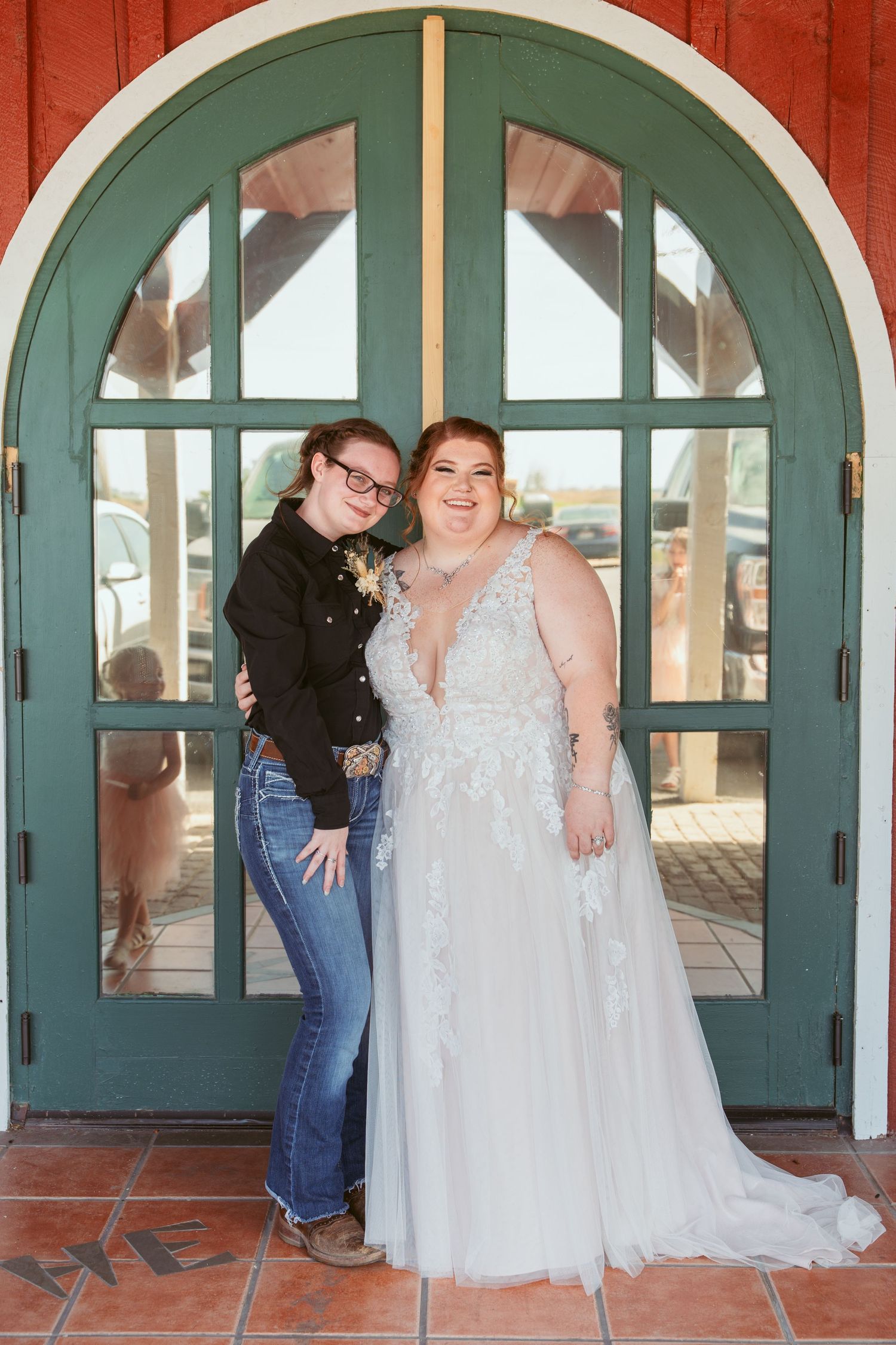 Two people pose together by teal arched door, one wearing white wedding gown.