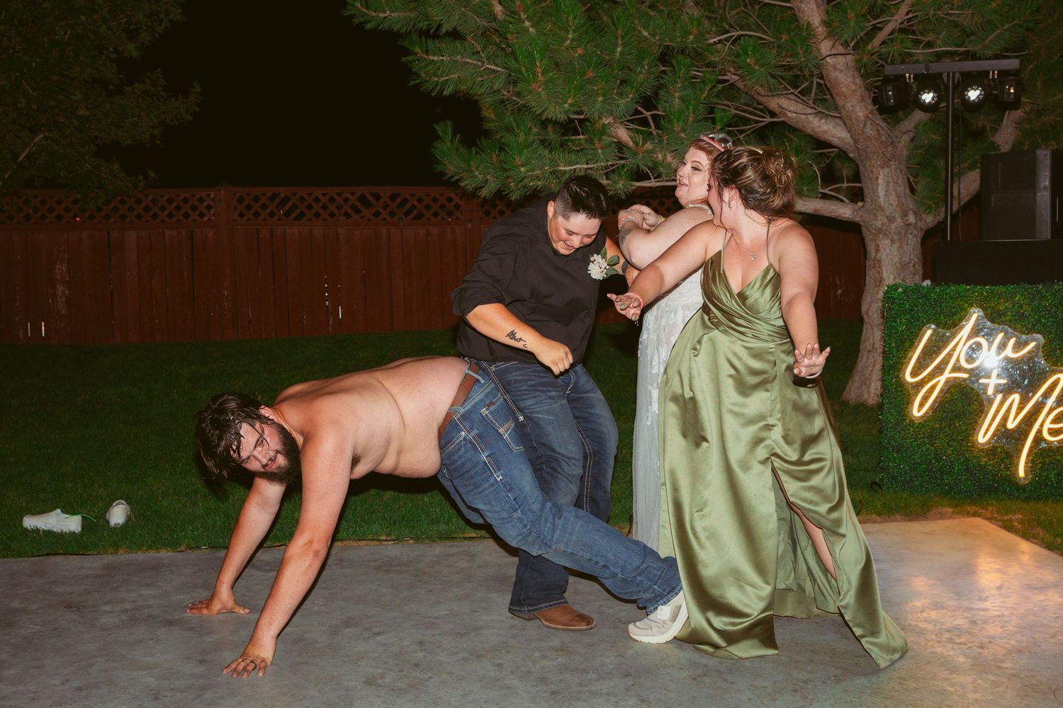 People performing playful wrestling moves on grass at night.