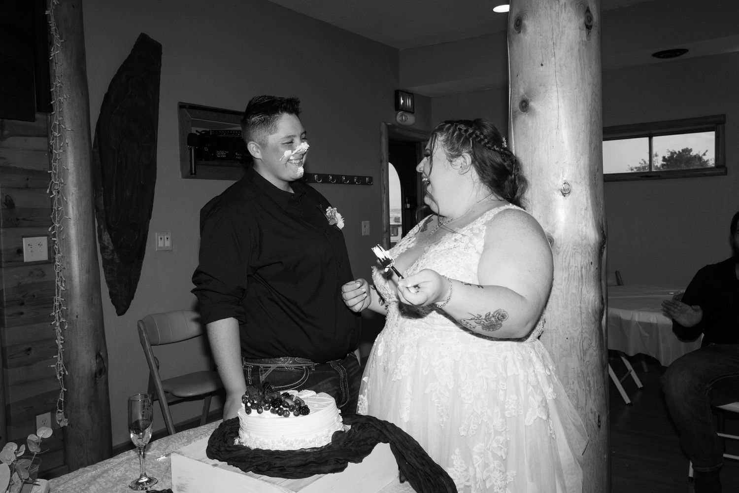 Black and white photo of a wedding cake feeding tradition at a reception.