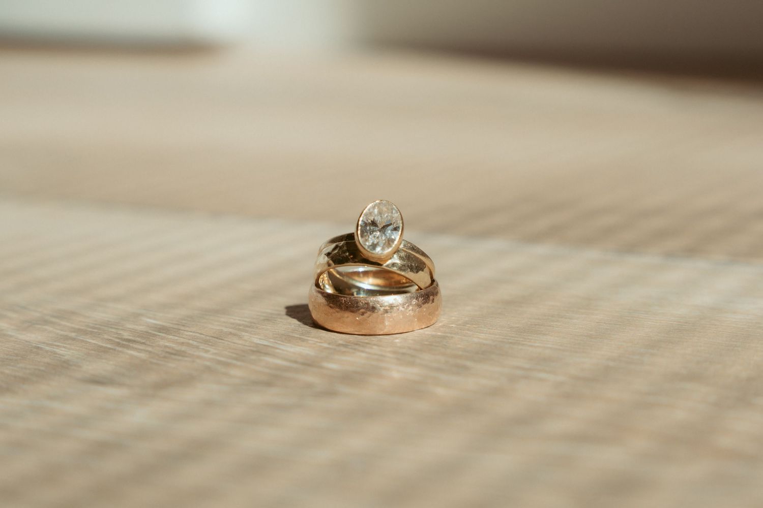 Close-up of gold wedding bands resting on a neutral beige surface.