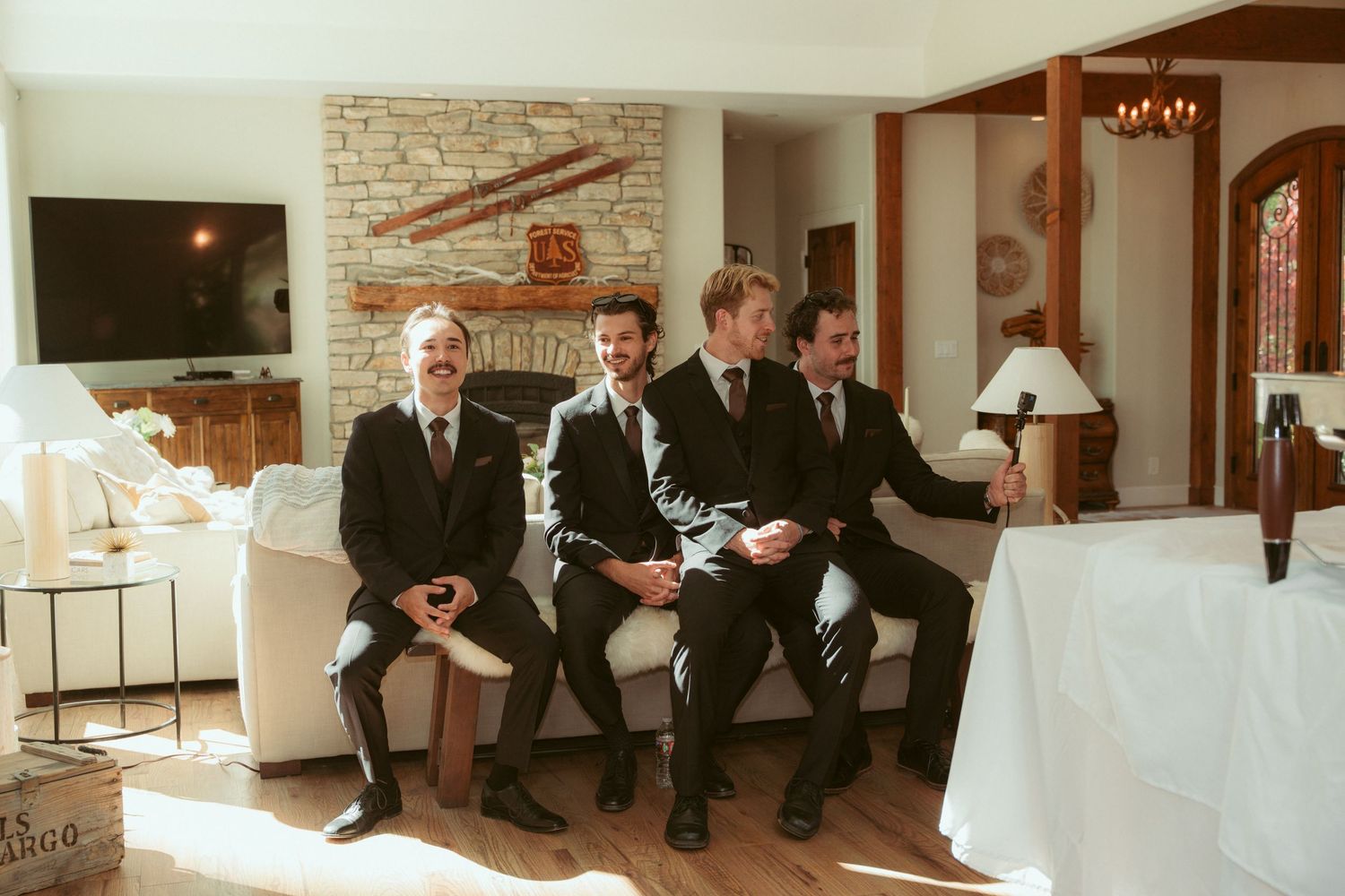 Group of men in formal attire sitting and chatting in an elegant room with brick walls.