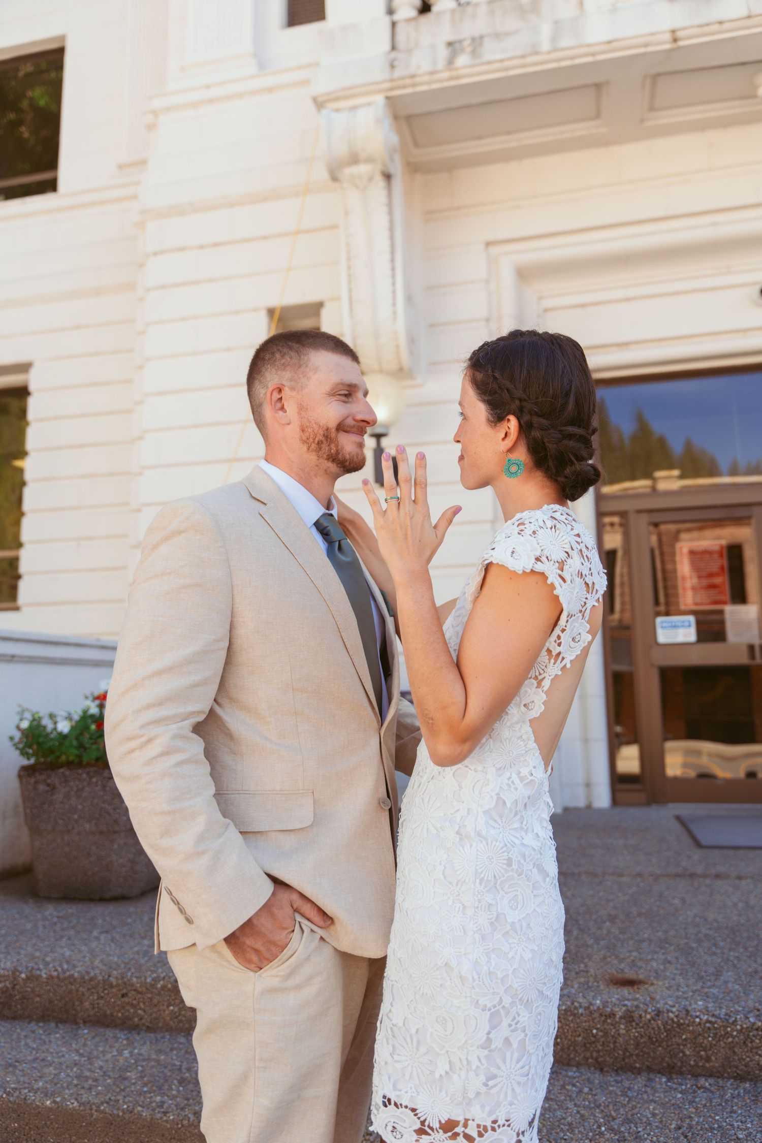 A couple shares joyful moments outside a historic building on their wedding day.