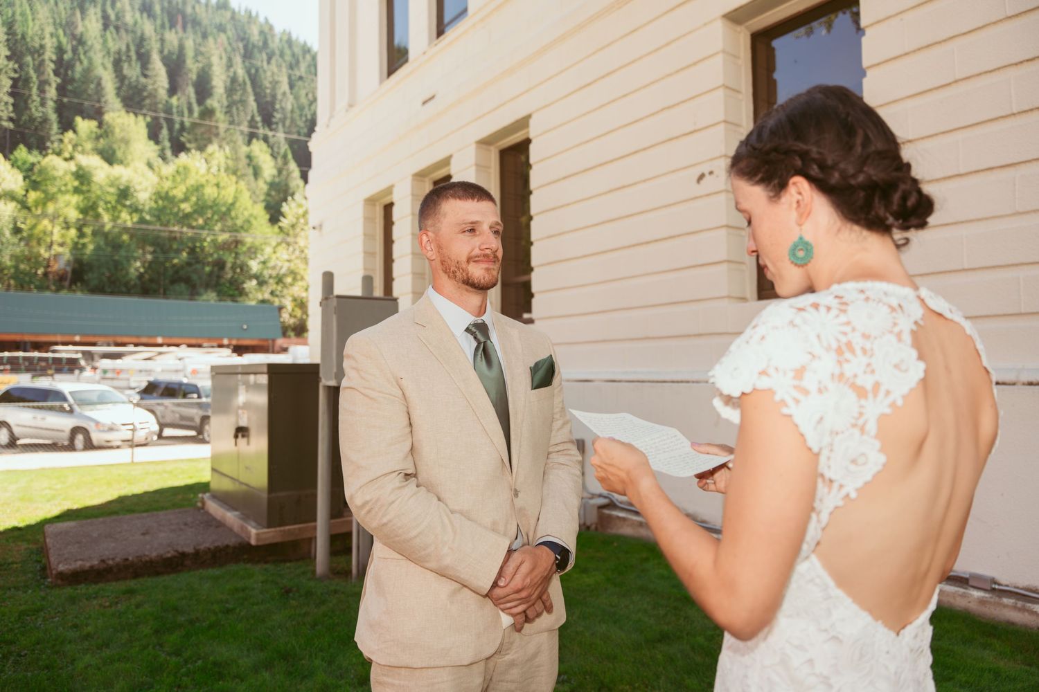 A couple in wedding attire shares an intimate moment reading letters outdoors.