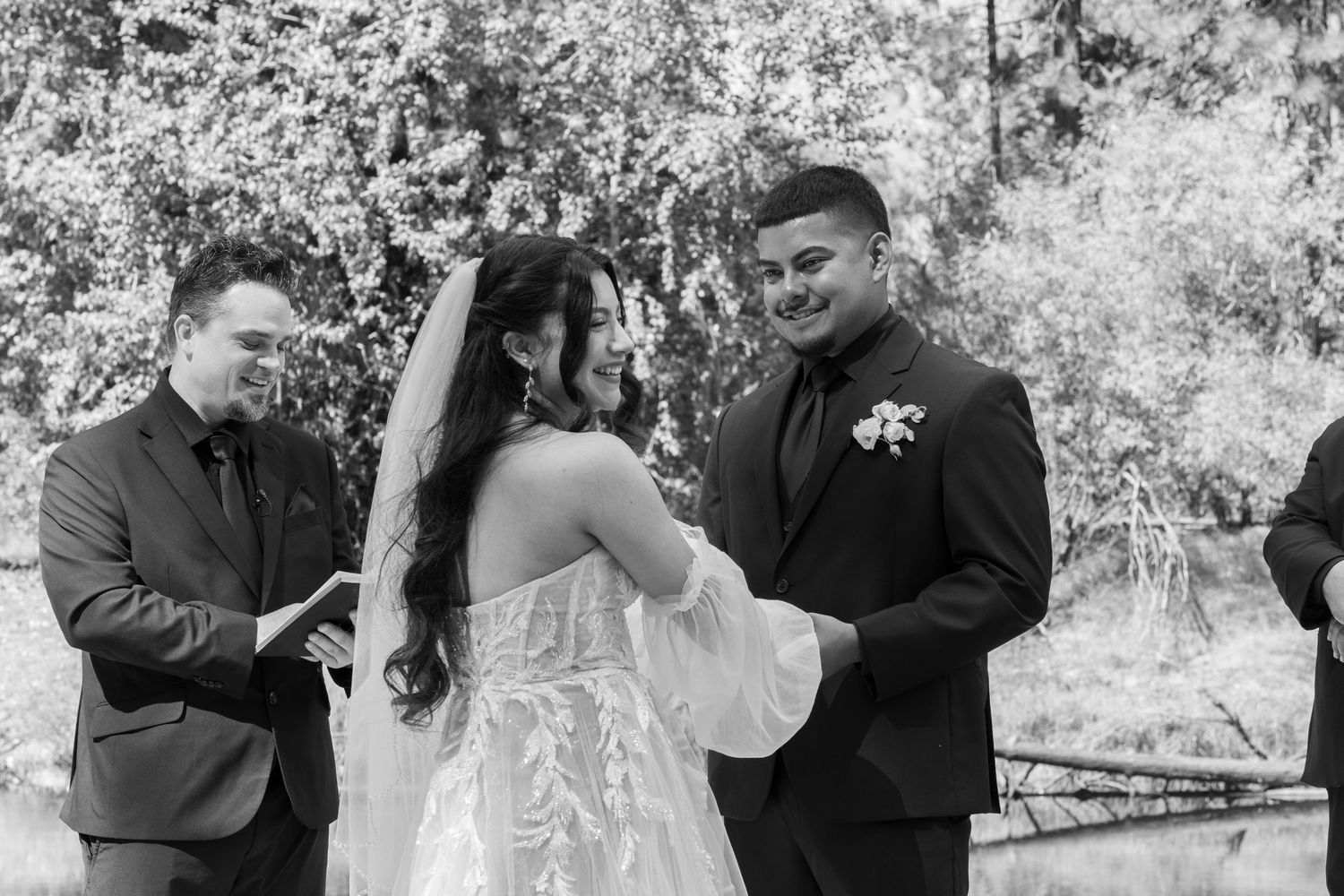 A wedding ceremony unfolds in a serene black and white outdoor setting.