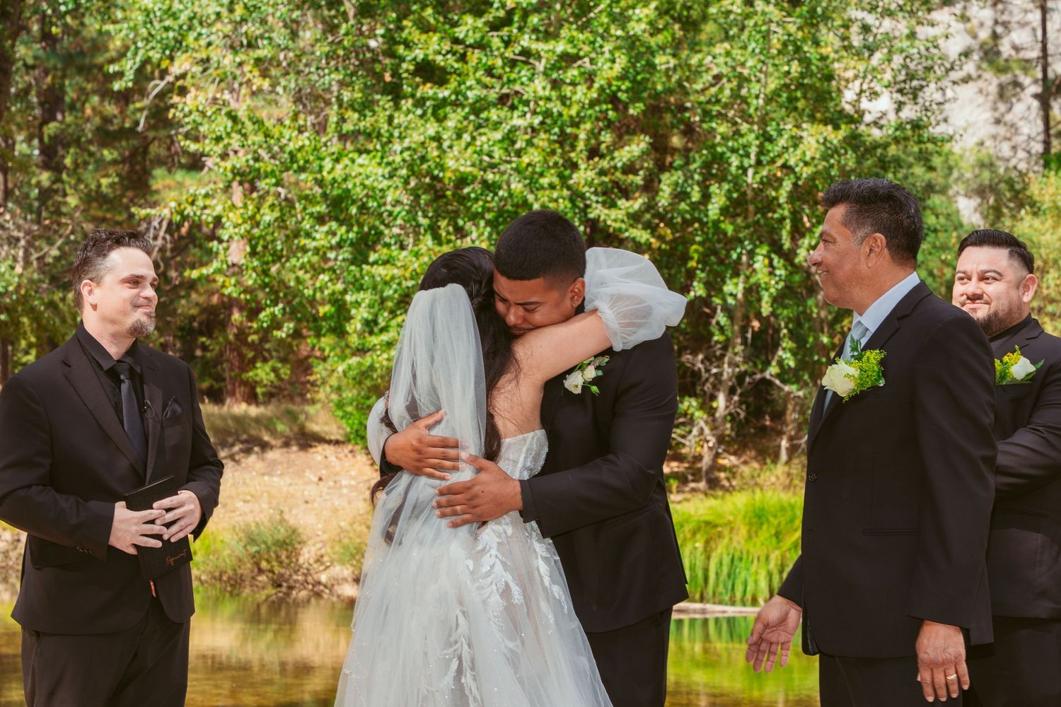 Wedding party gathered under pine trees with Yosemite's iconic granite walls in the distance.