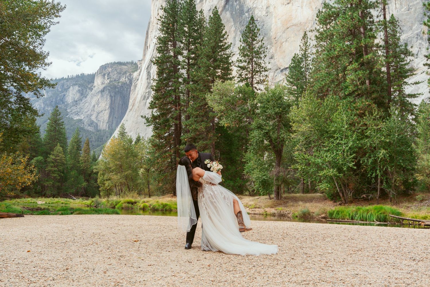 Wedding couple photographed from afar against the dramatic landscape of Yosemite National Park.