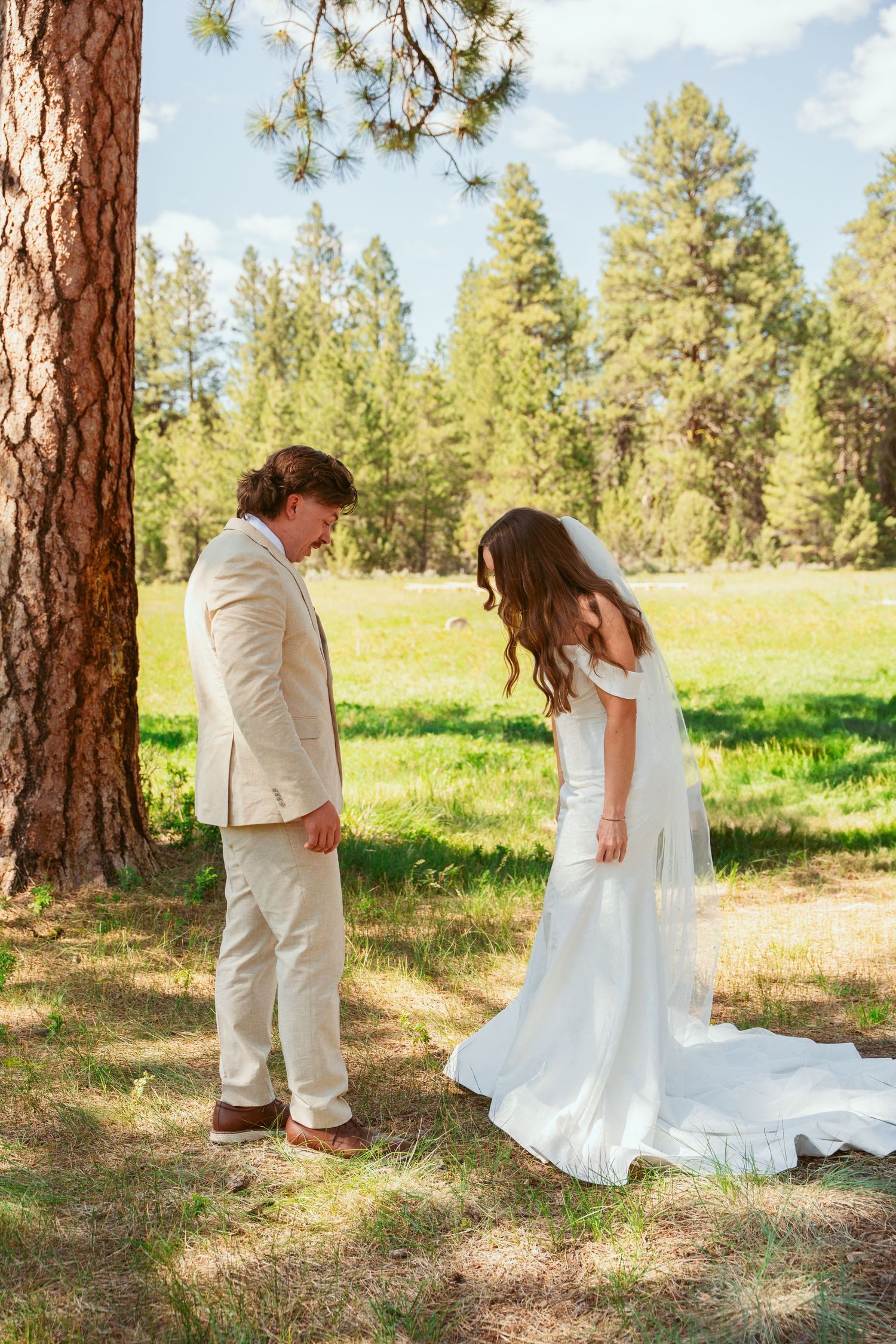 Bride and partner share candid reactions during their first look photo sequence in a forest meadow.