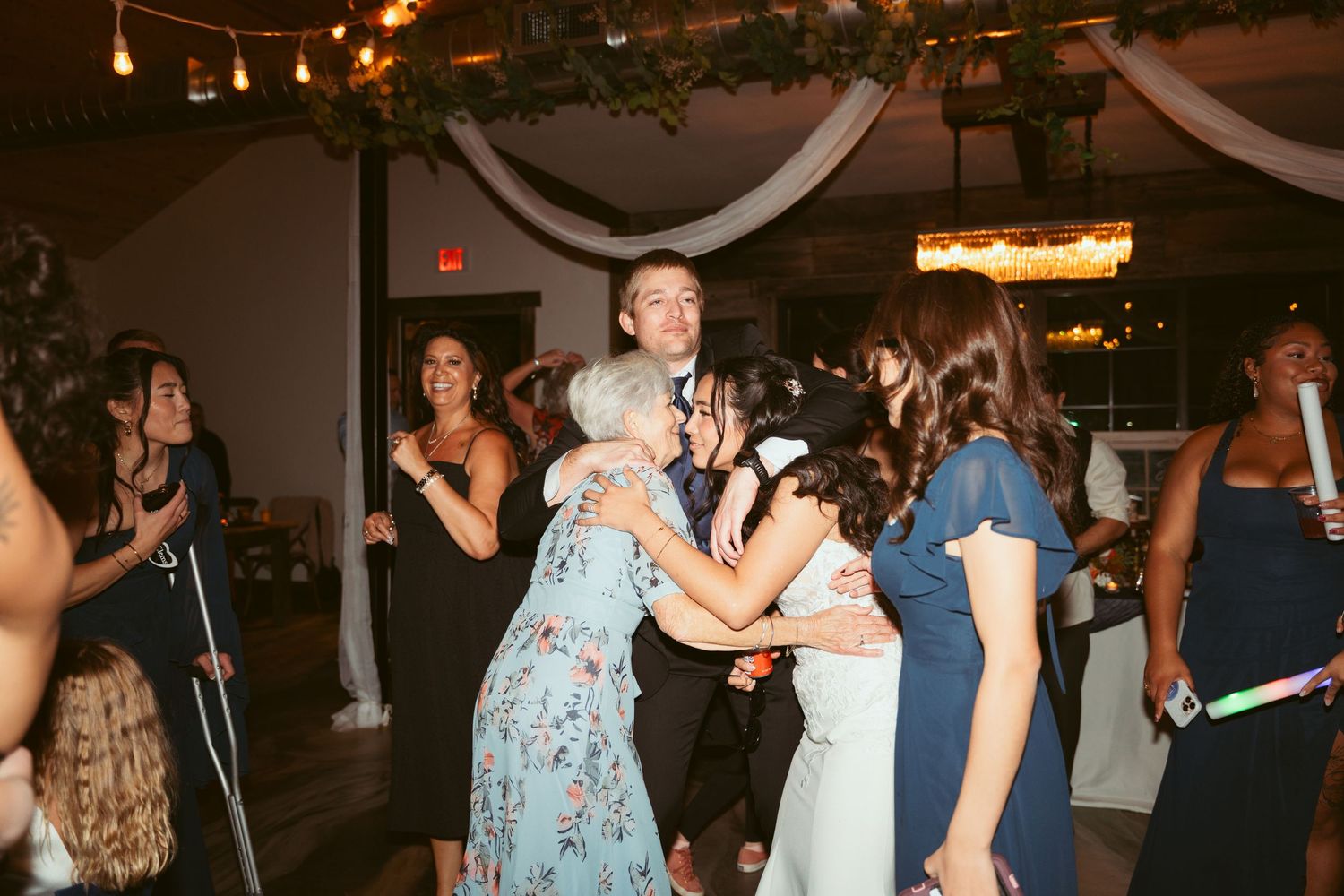 Crowded dance floor at a formal event with guests in blue and dark colored attire.