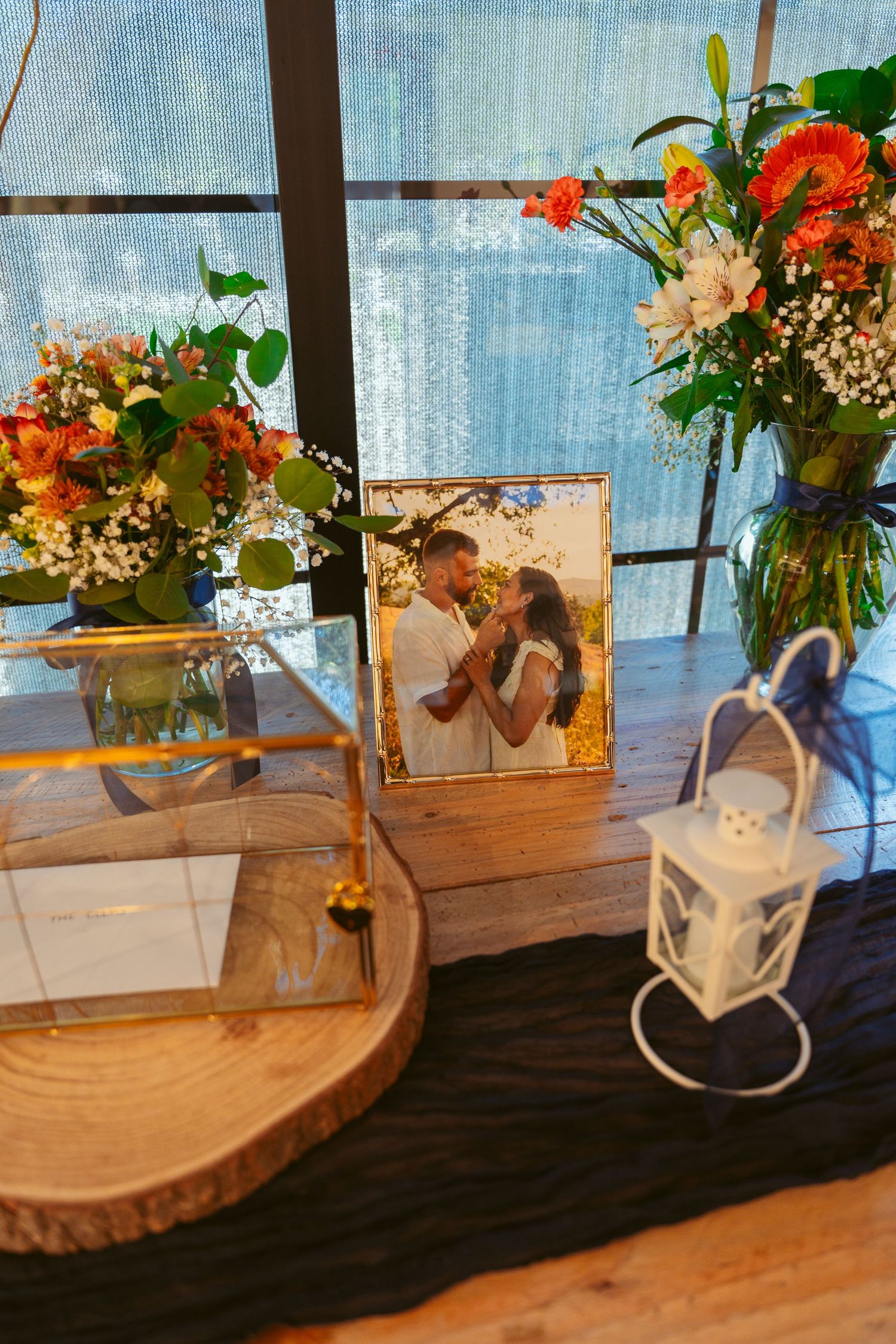 Rustic floral centerpieces with orange and white flowers arranged in white vases on wooden slices.