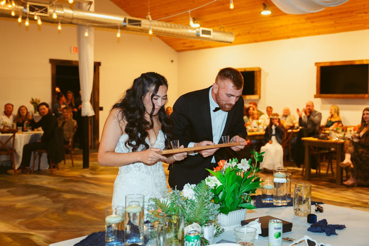 Elegant wedding reception setup with decorative lighting and floral arrangements on tables.
