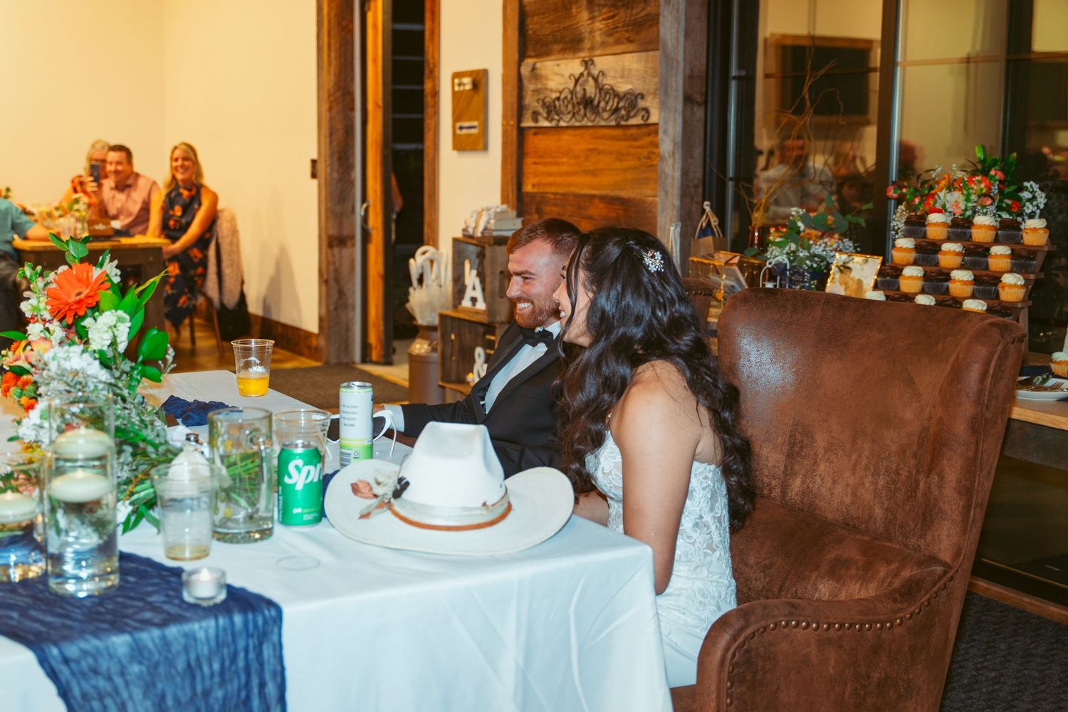 Wedding reception venue with elegant table settings and rustic wooden ceiling beams.