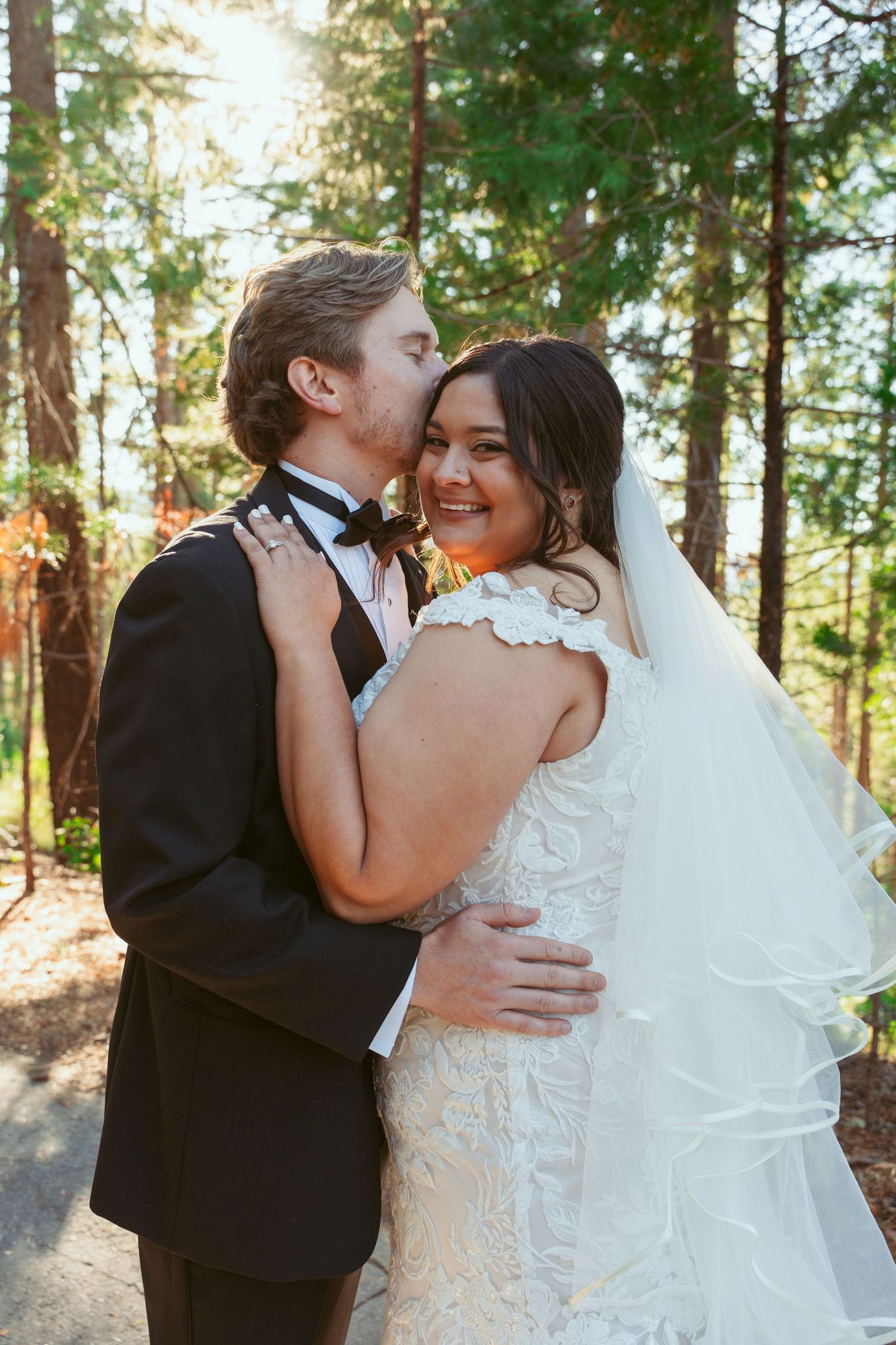 A loving embrace between newlyweds in a forest setting.