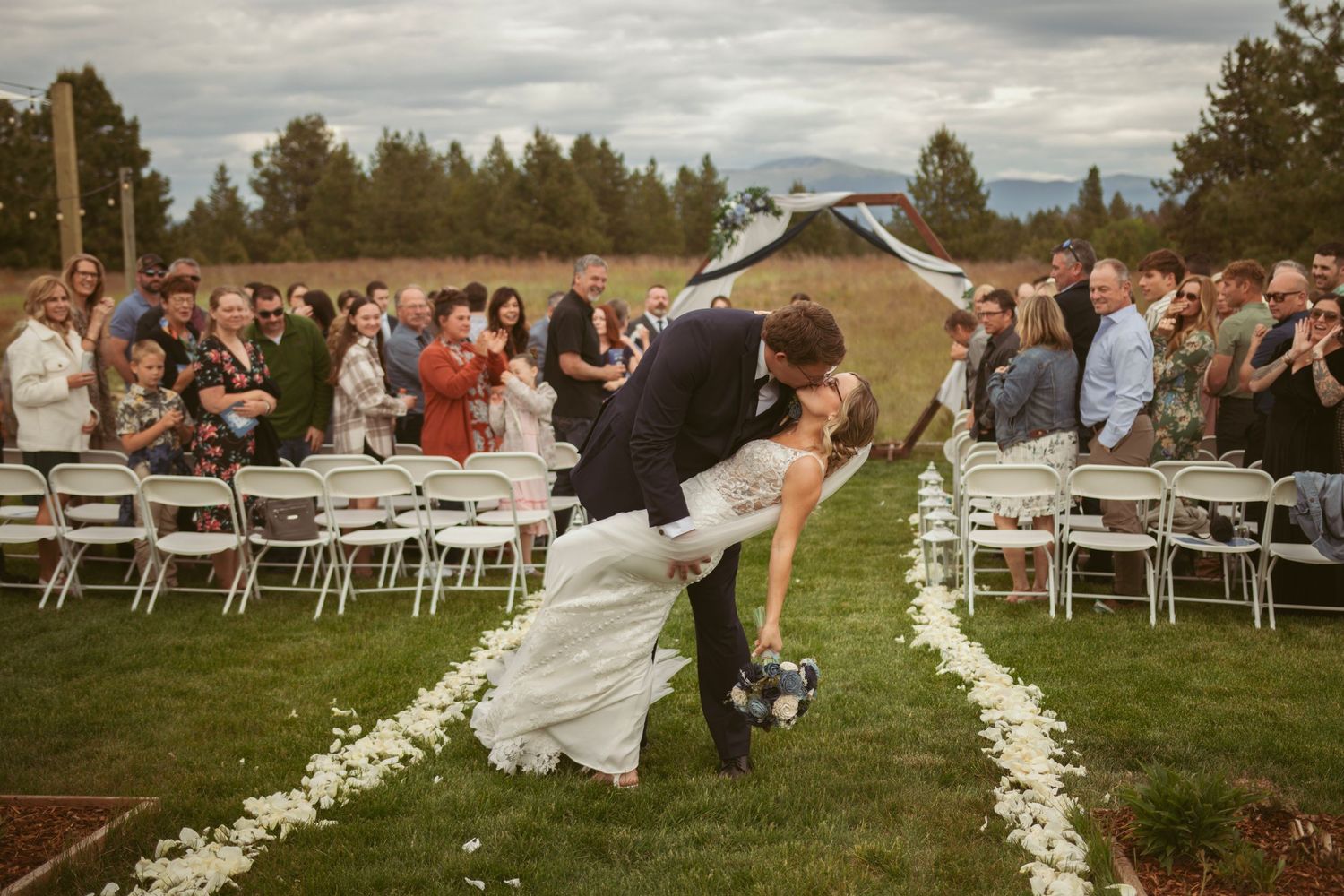 An outdoor wedding ceremony setup with white flower petals lining the aisle.
