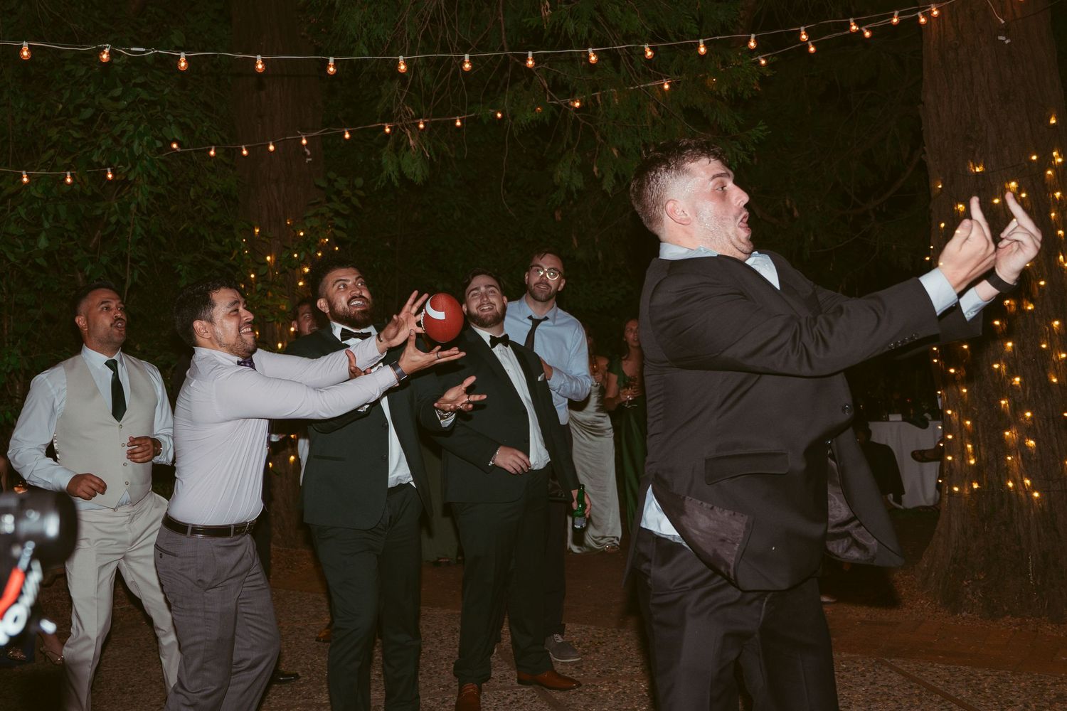 String lights illuminate an outdoor wedding reception as guests dance in the evening.