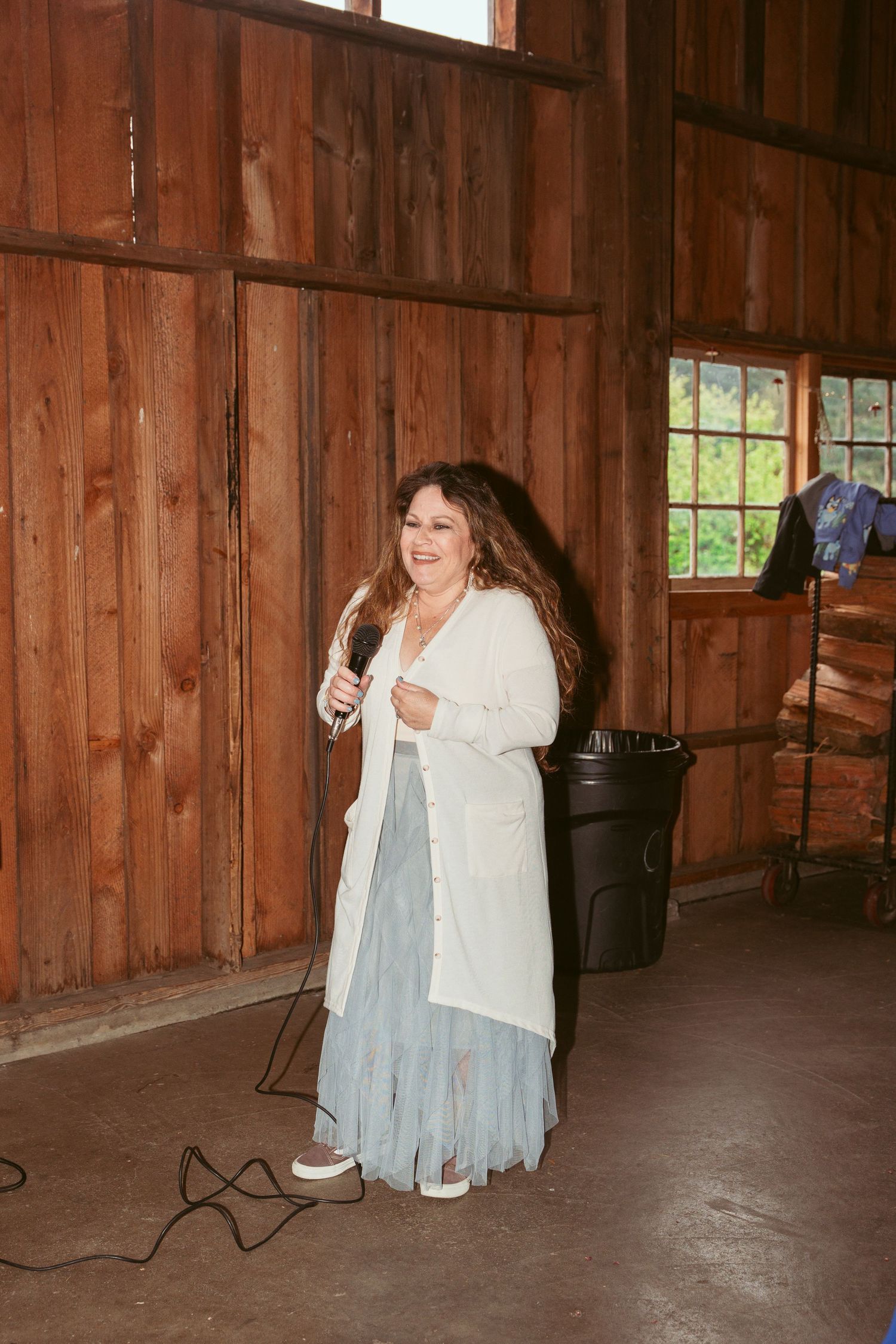 People dancing and celebrating in a rustic wooden barn venue with natural lighting.