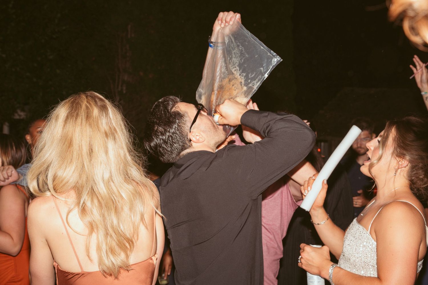 People dancing and socializing at a dimly lit party or celebration event.