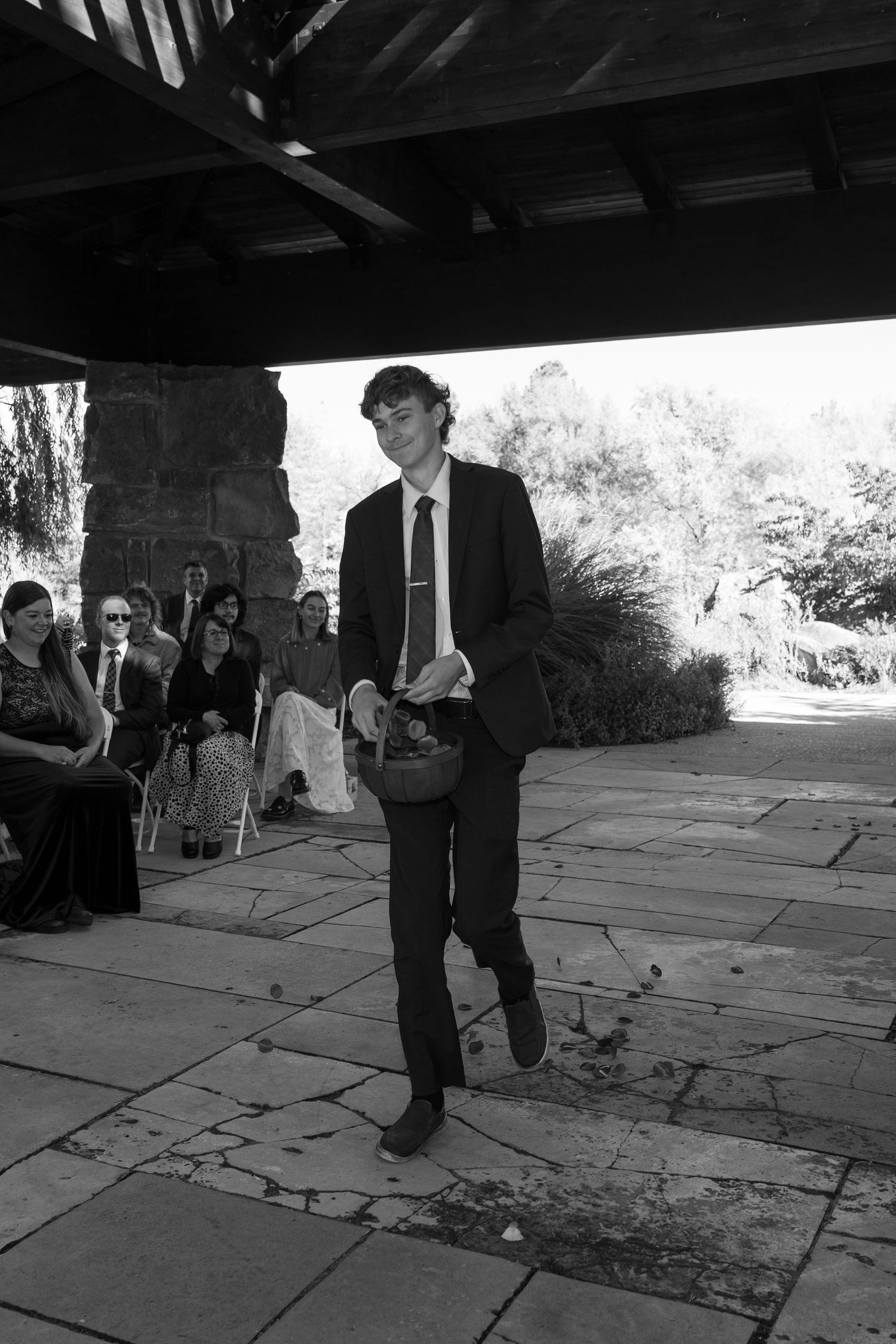Black and white photo capturing movement of people on a stone patio during an event.