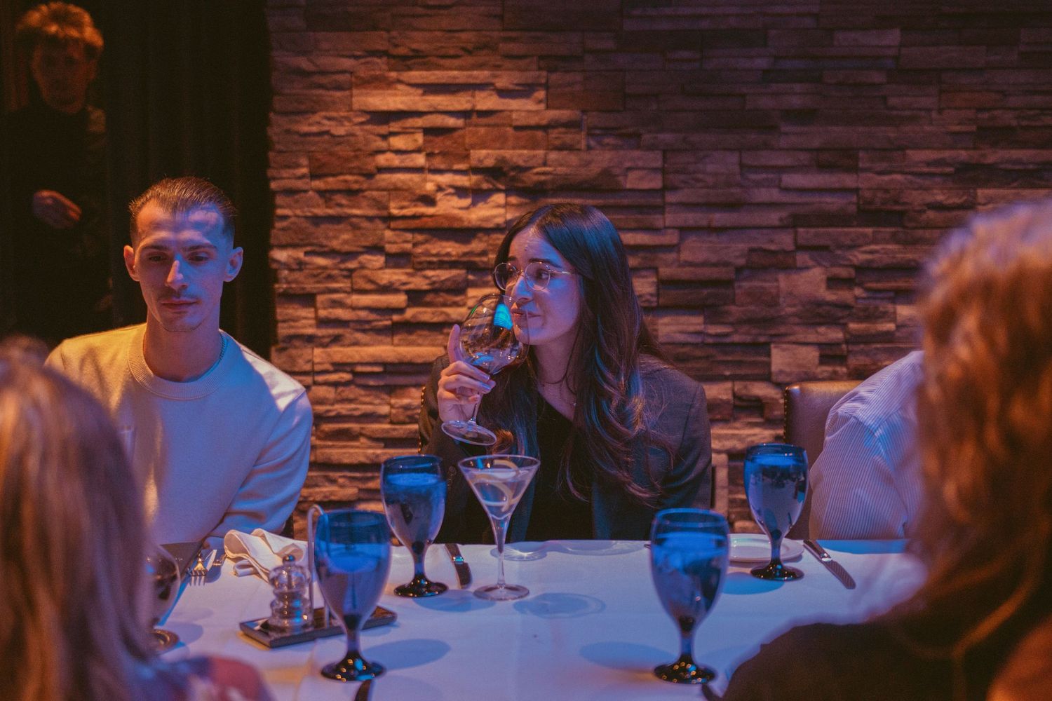 Dining tables with stone wall backdrop and ambient lighting at wedding reception.