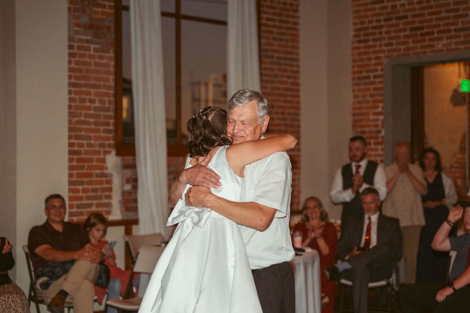Elegant dance performance in a historic brick-walled event space with decorative lighting.