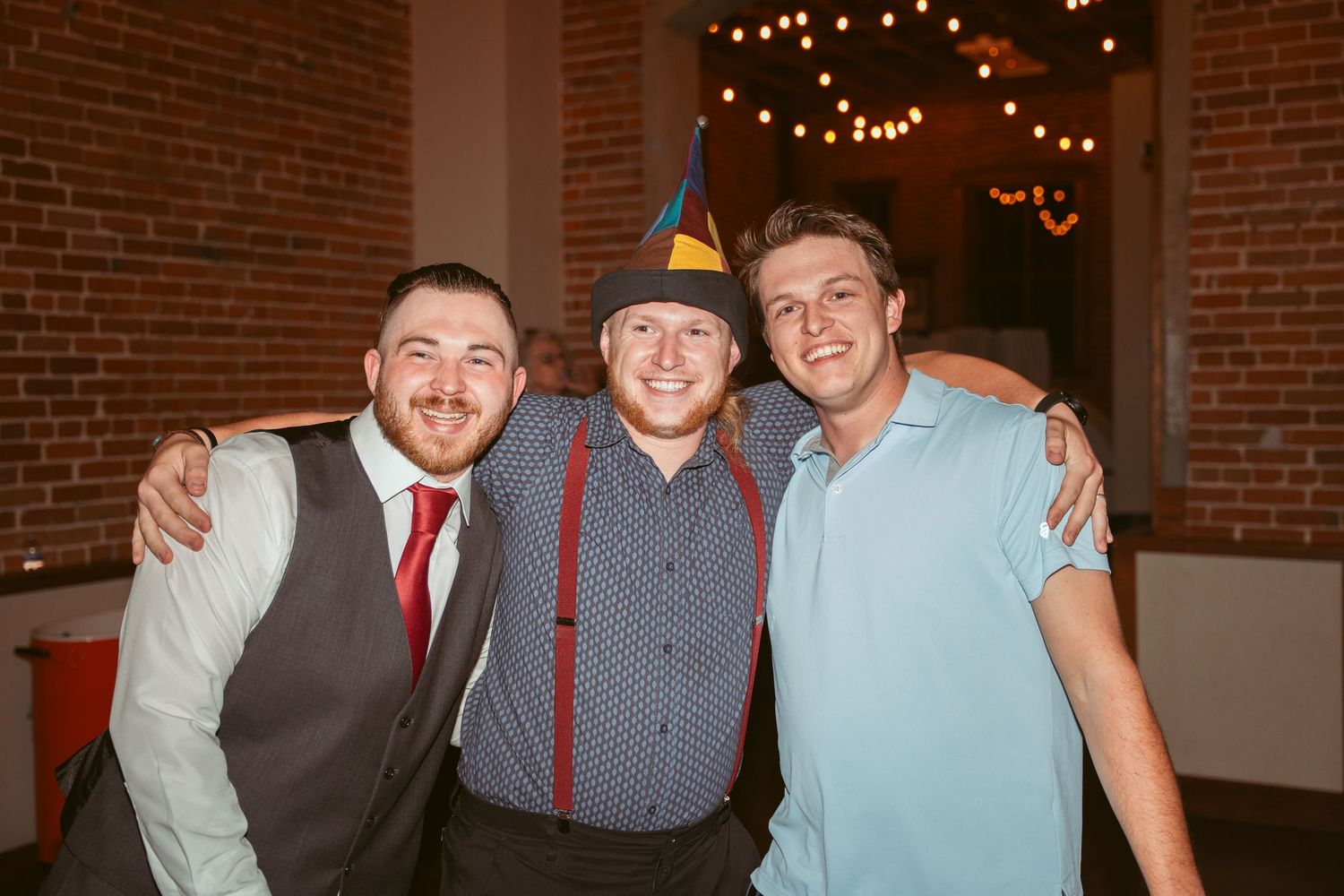 Friends celebrating together at a wedding reception in front of exposed brick walls.