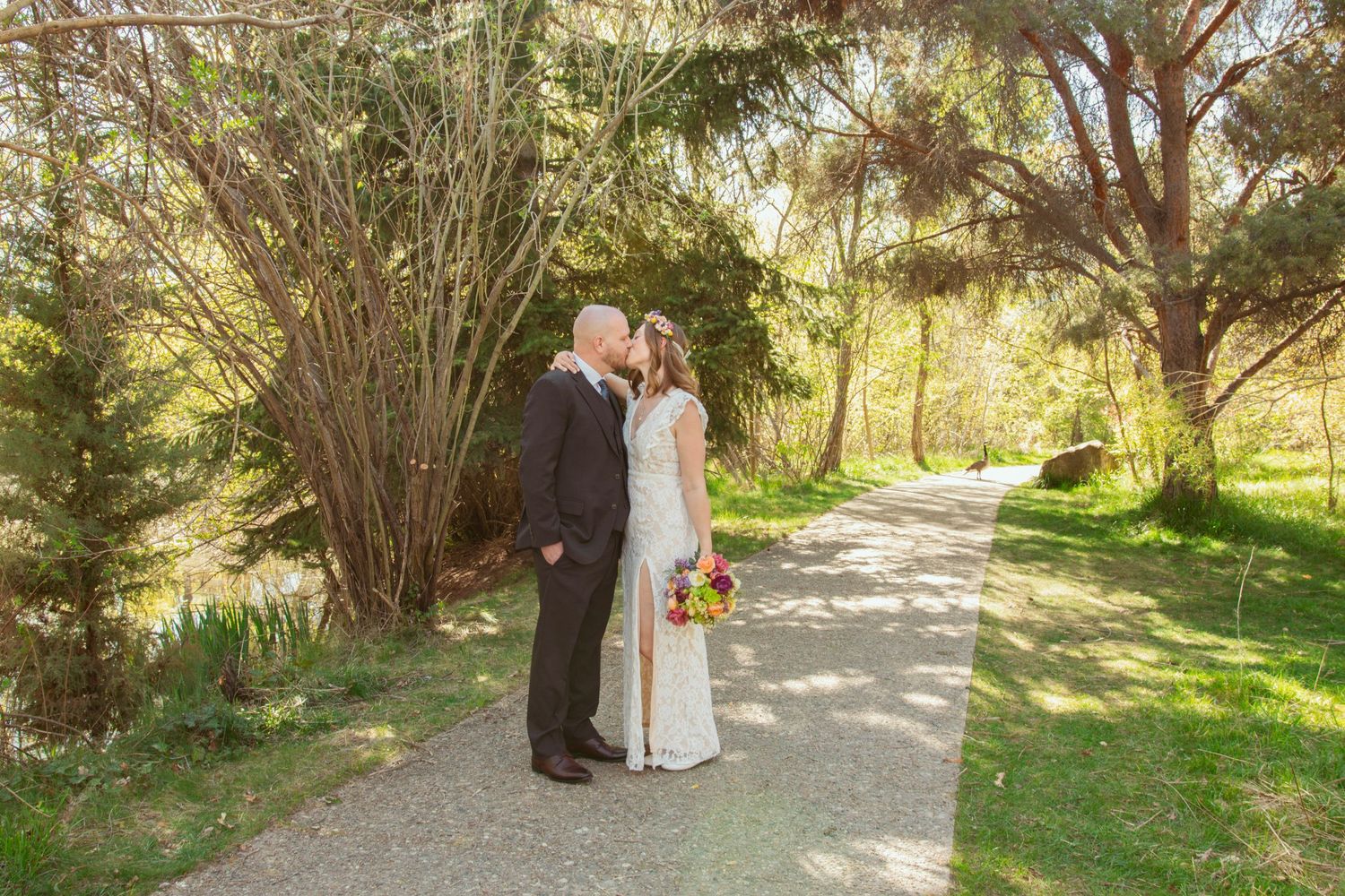 A wedding couple shares an intimate moment on a garden path surrounded by lush greenery.