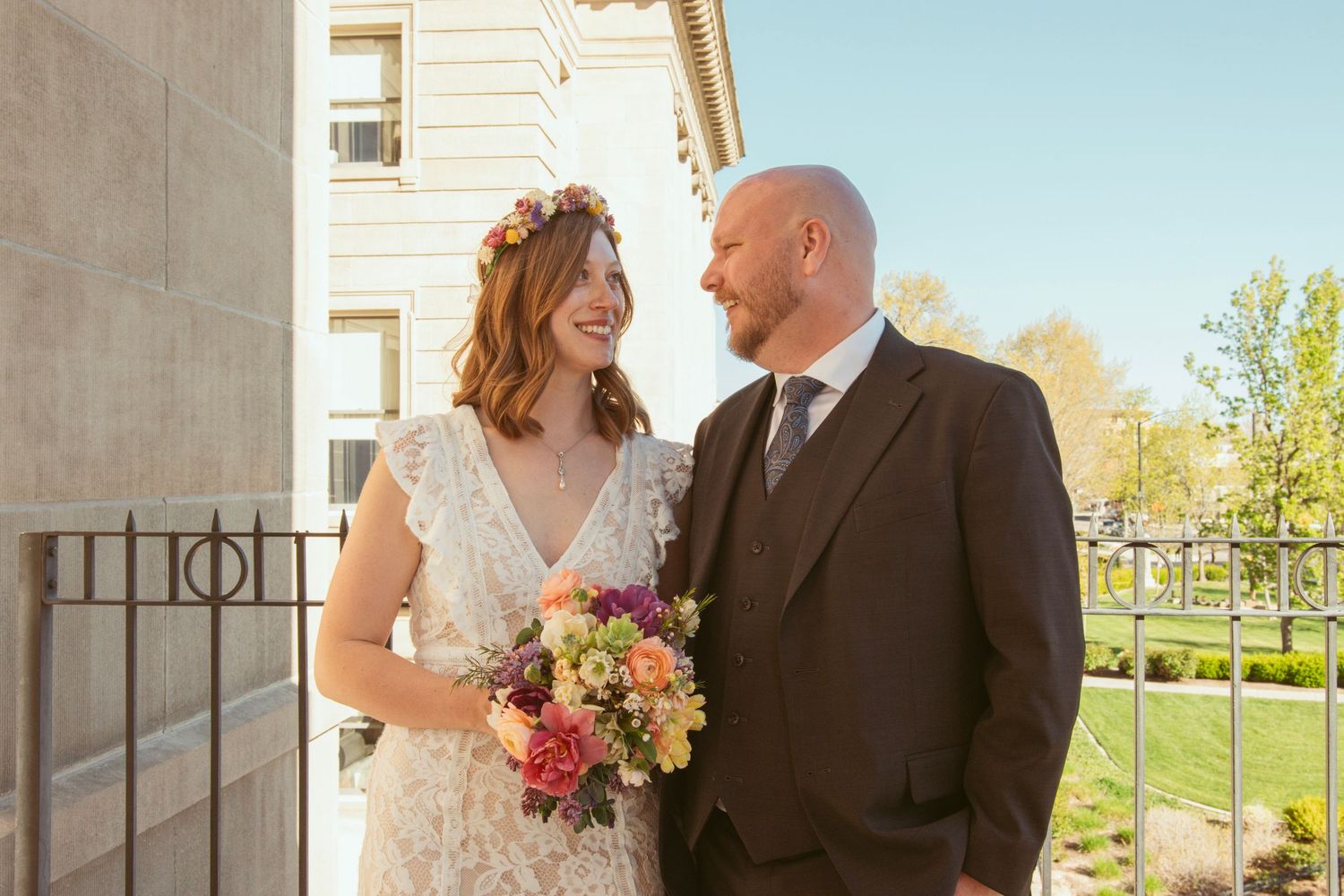 Newlyweds posing for romantic portraits in front of a light-colored building.