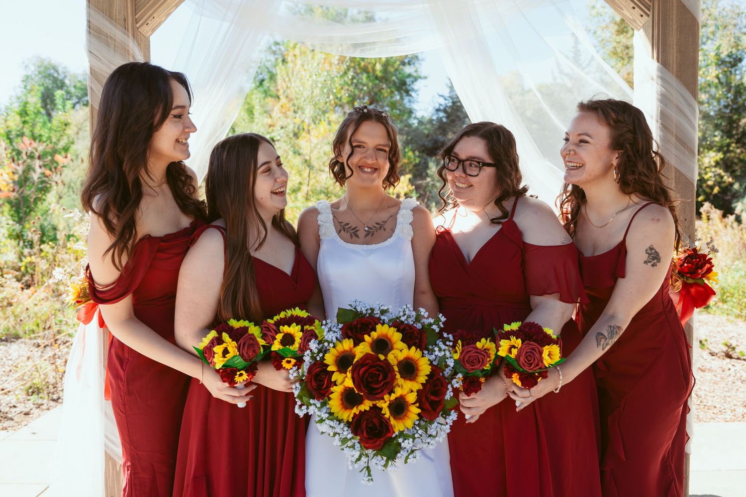 Candid shots of bridal party in burgundy dresses with sunflower bouquets laughing together.