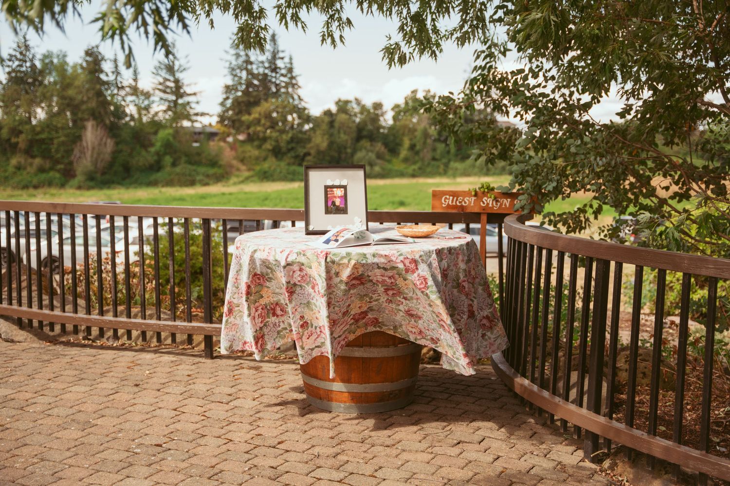 Outdoor wedding venue with rustic wooden deck and natural greenery overlooking scenic landscape.