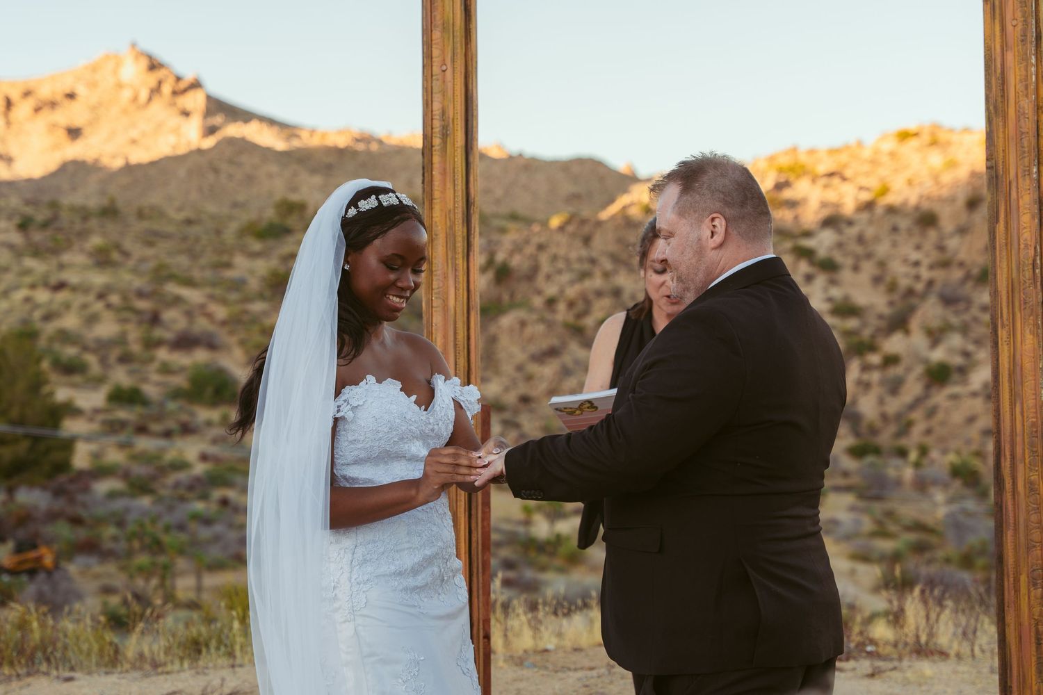 A couple shares their first dance at sunset with desert mountains in the background.