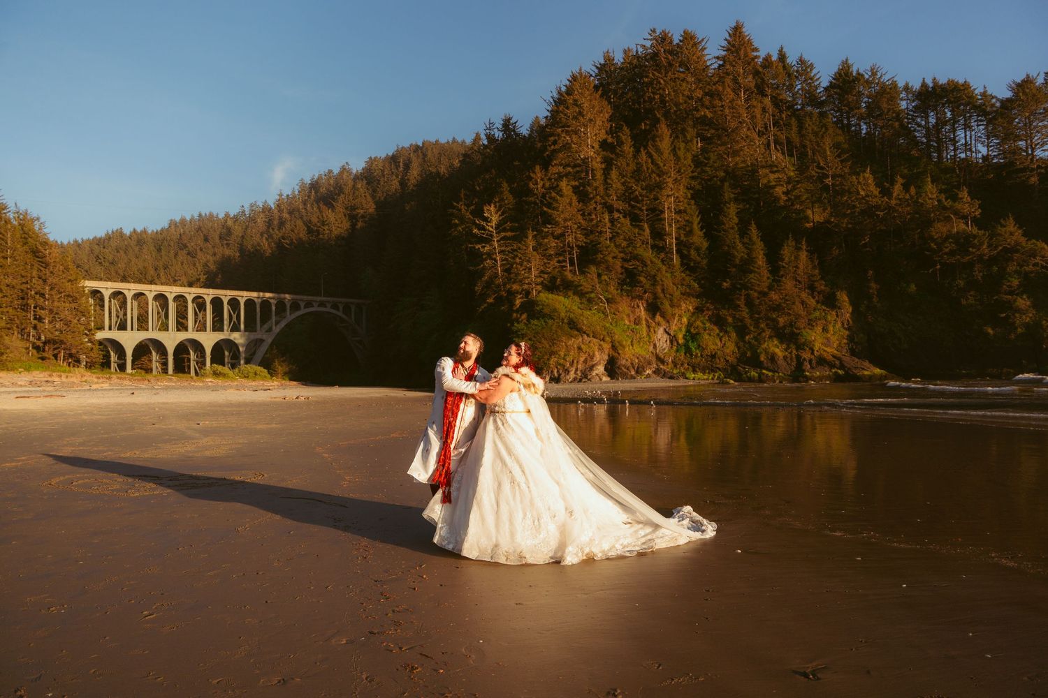 Sunset wedding photos on a beach with mountains and arches in the background.