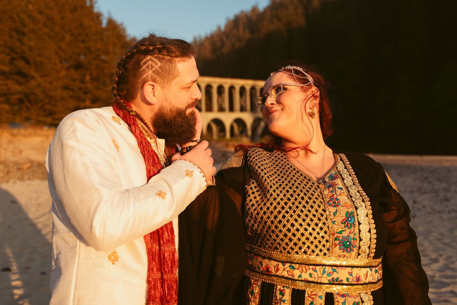 A couple sharing laughter during their beach ceremony at golden hour.