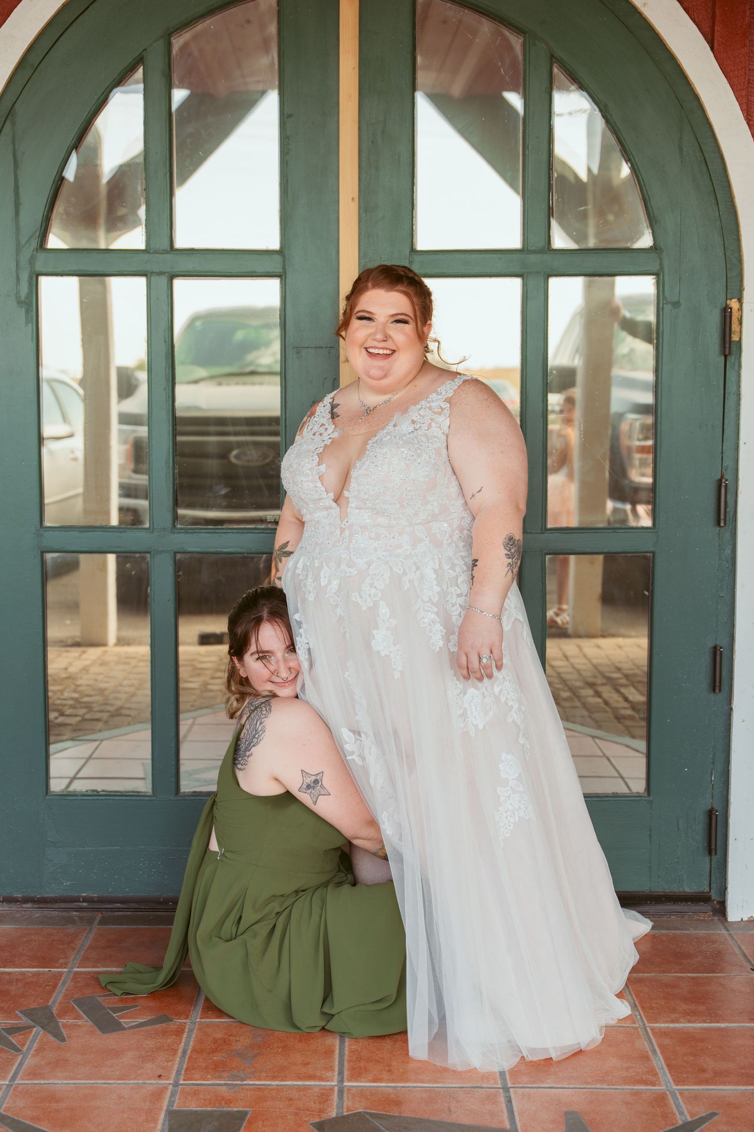Wedding couple poses in front of arched green doorways and terracotta walls.
