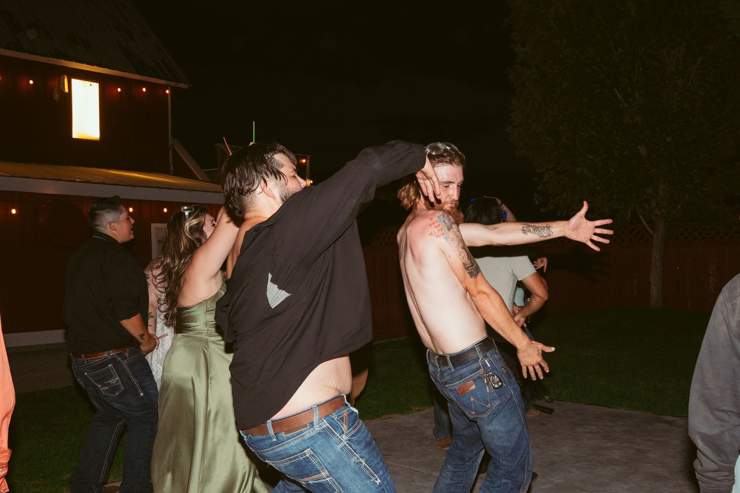 Wedding guests dancing energetically at outdoor nighttime celebration.