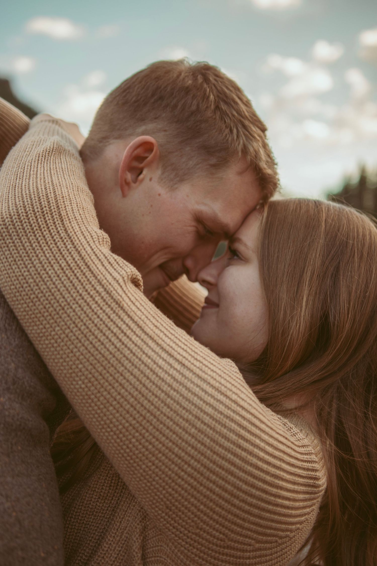 Intimate close-up of a couple in warm sweaters sharing a tender moment.