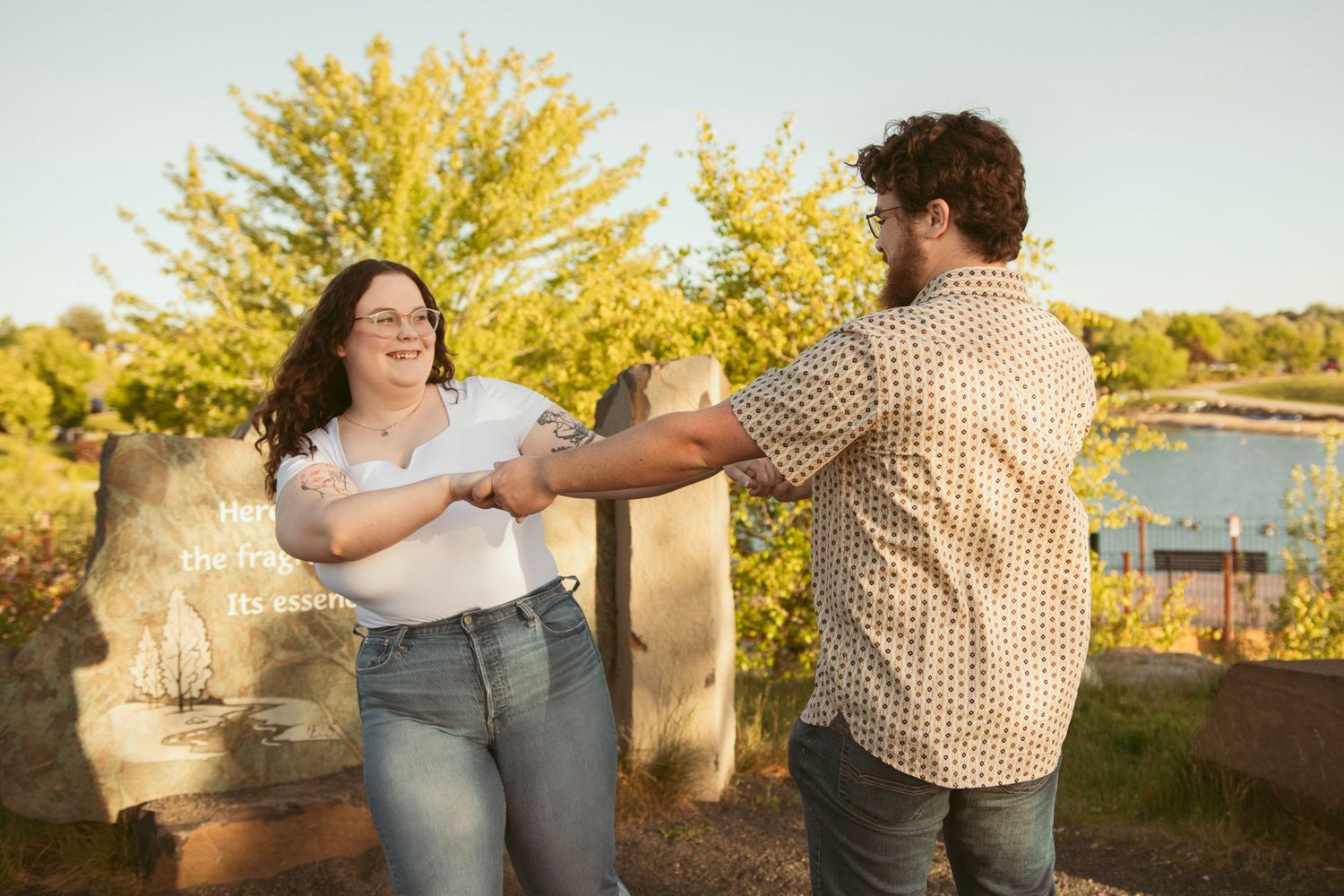 Couple posing playfully against autumn trees with golden sunlight filtering through.