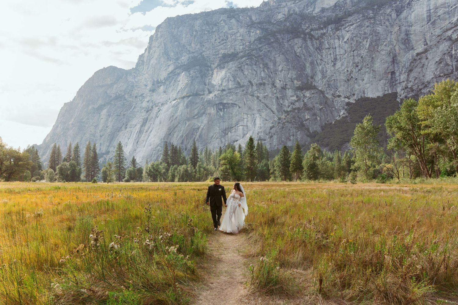 Wedding photography session in Yosemite's meadow with majestic mountain backdrop.