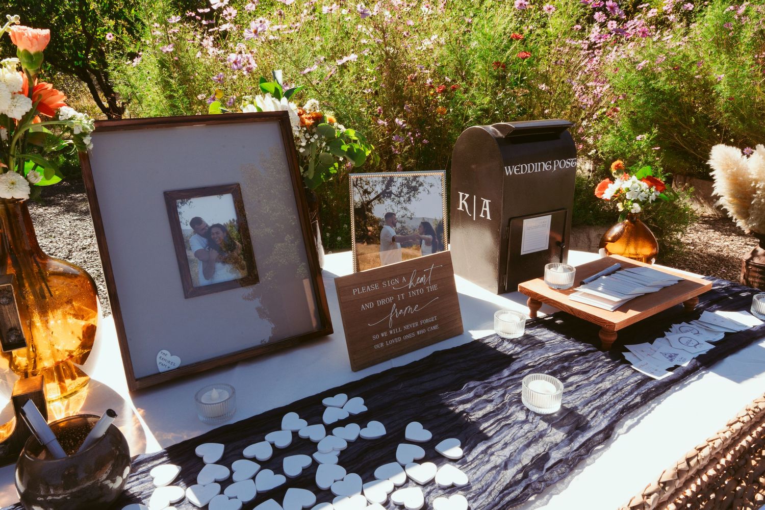 Wedding memory table with photo frames, black tablecloth, and orange floral accents.