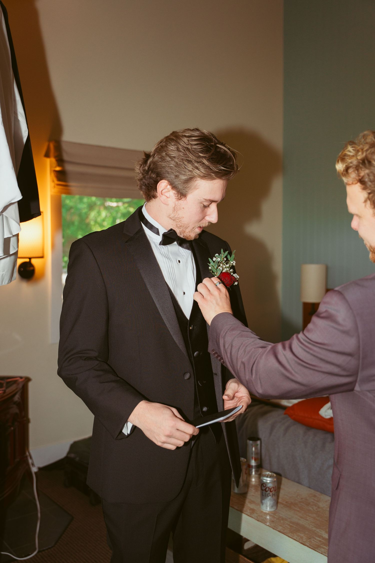 Wedding party members adjusting formal attire and helping each other prepare.