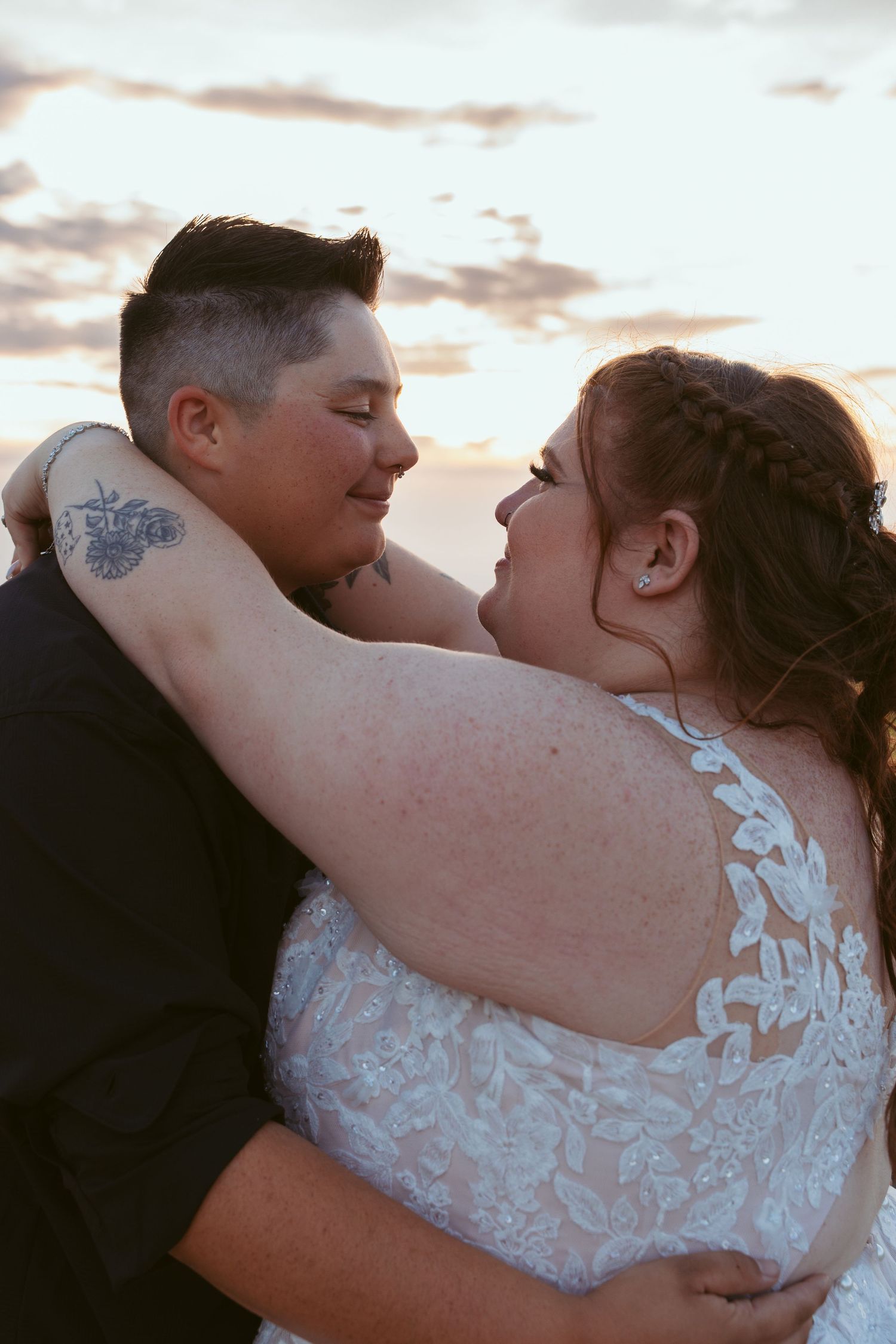 Couple embraces tenderly during sunset wedding photoshoot with soft golden lighting.