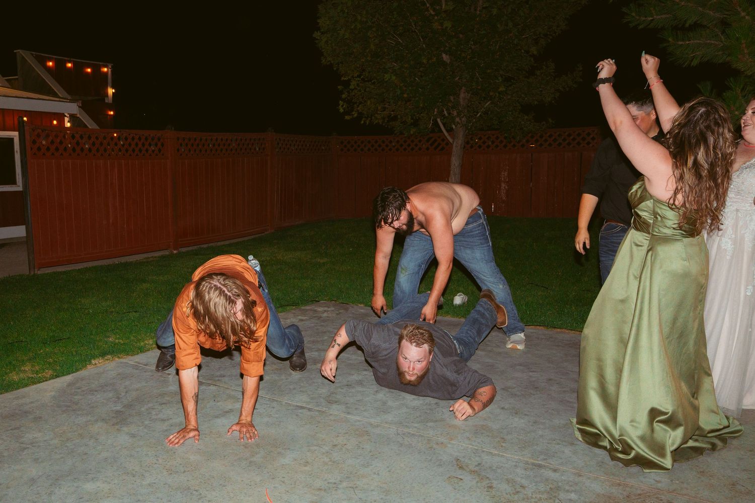 Wedding guests and a dog create silly poses during nighttime celebrations.