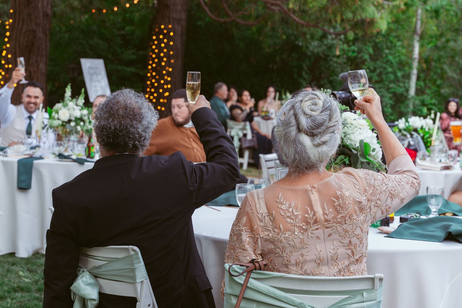 Evening wedding reception tables decorated with string lights and floral centerpieces.