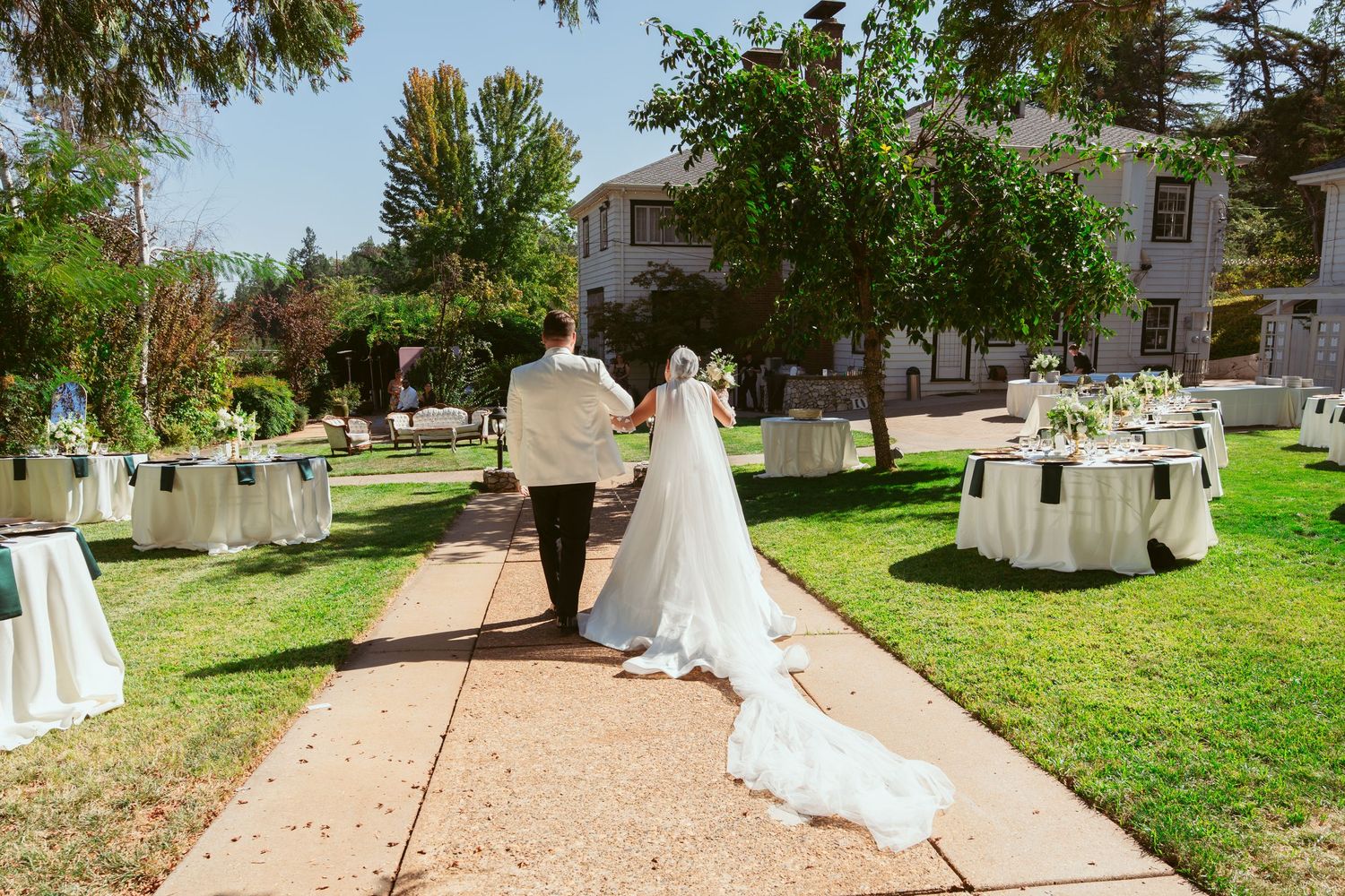 Outdoor wedding venue with garden pathways and white chairs set up for ceremony.