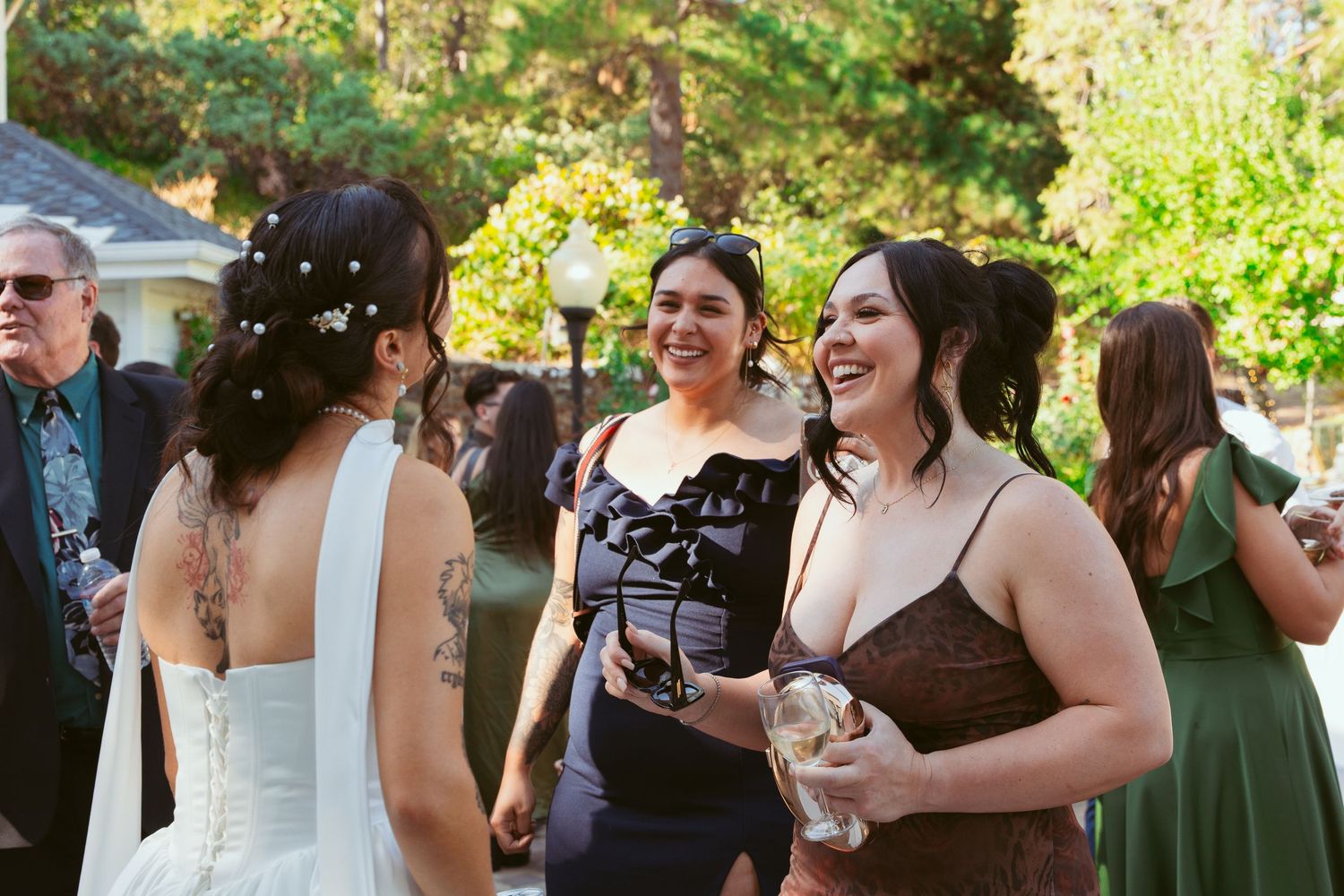 Wedding guests mingle and celebrate during an outdoor daytime garden reception.