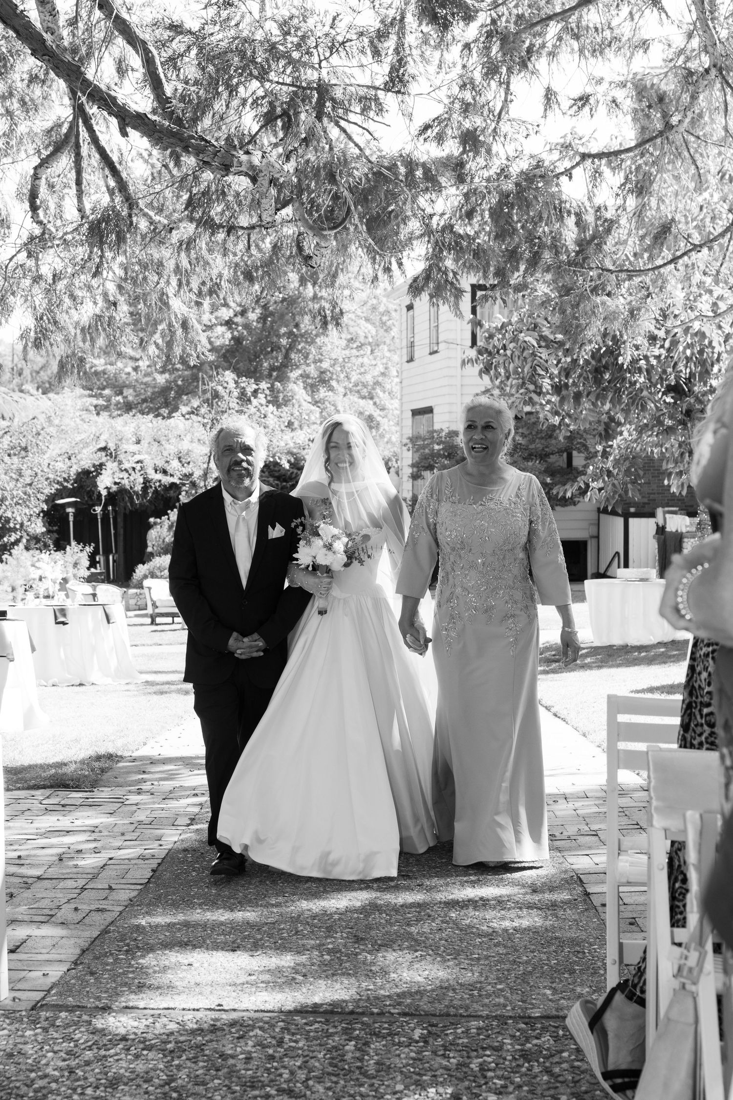 Black and white photo of wedding processional under Spanish moss draped trees.