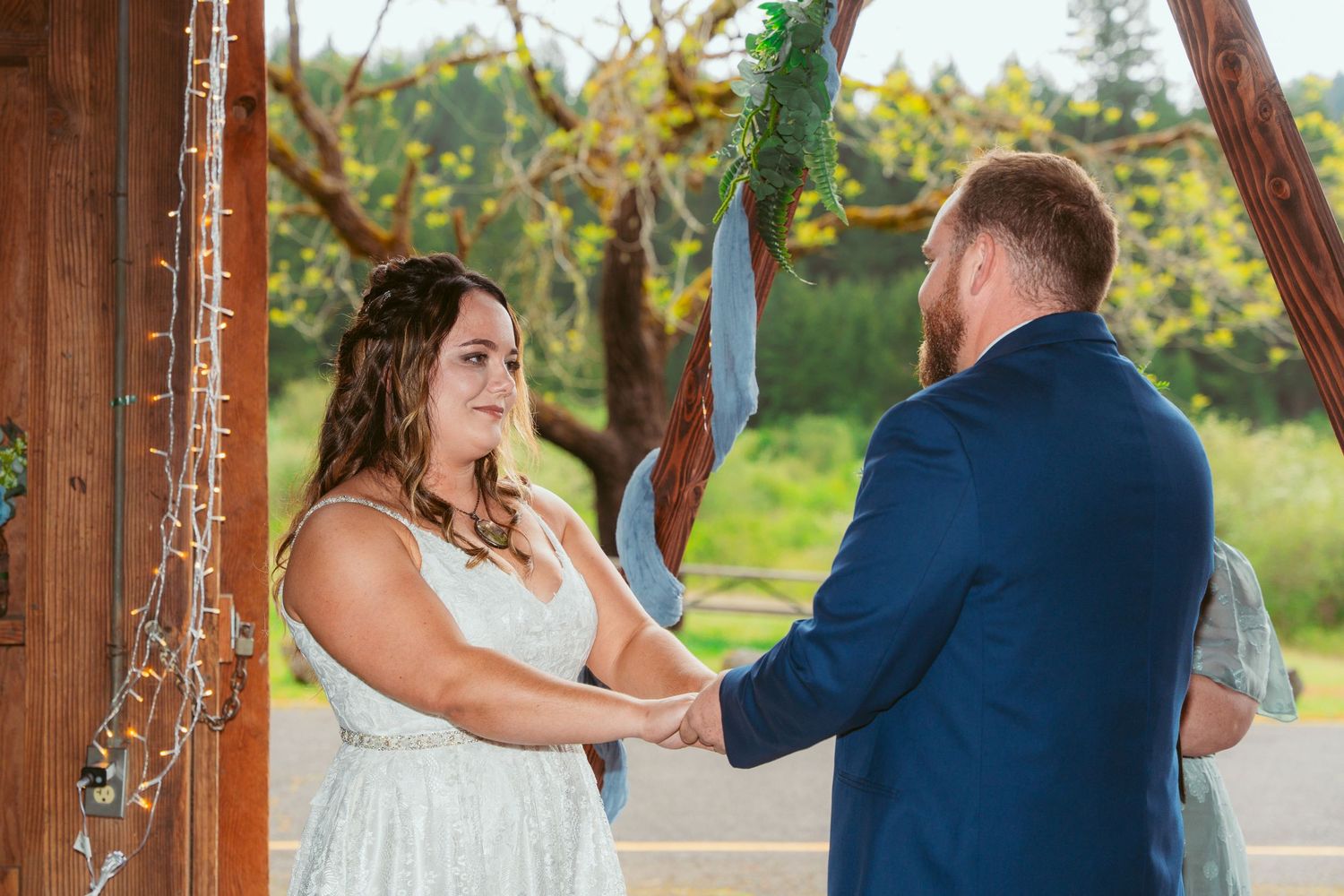 Emotional first dance moment captured in rustic barn venue with string lights and wooden beams.