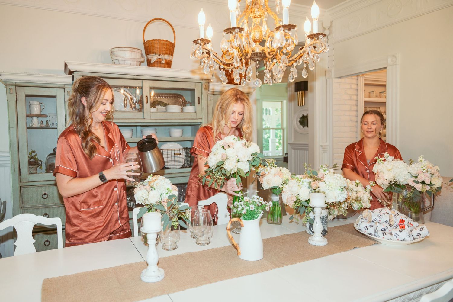 Dining room table decorated with white flowers and crystal chandelier for an intimate gathering.